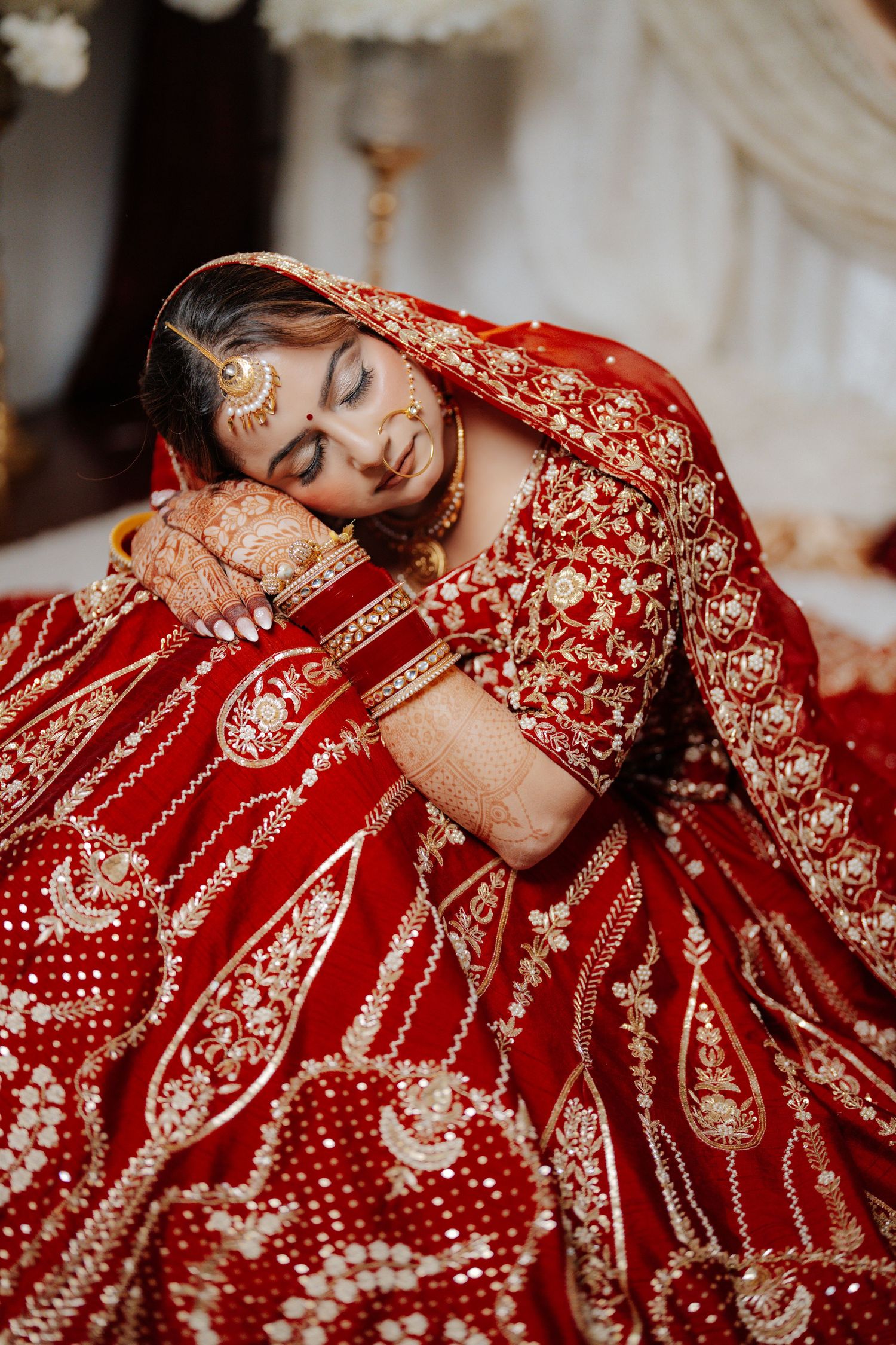 Artistic portrait showcasing the detailed embroidery of a traditional red Indian bridal lehenga.