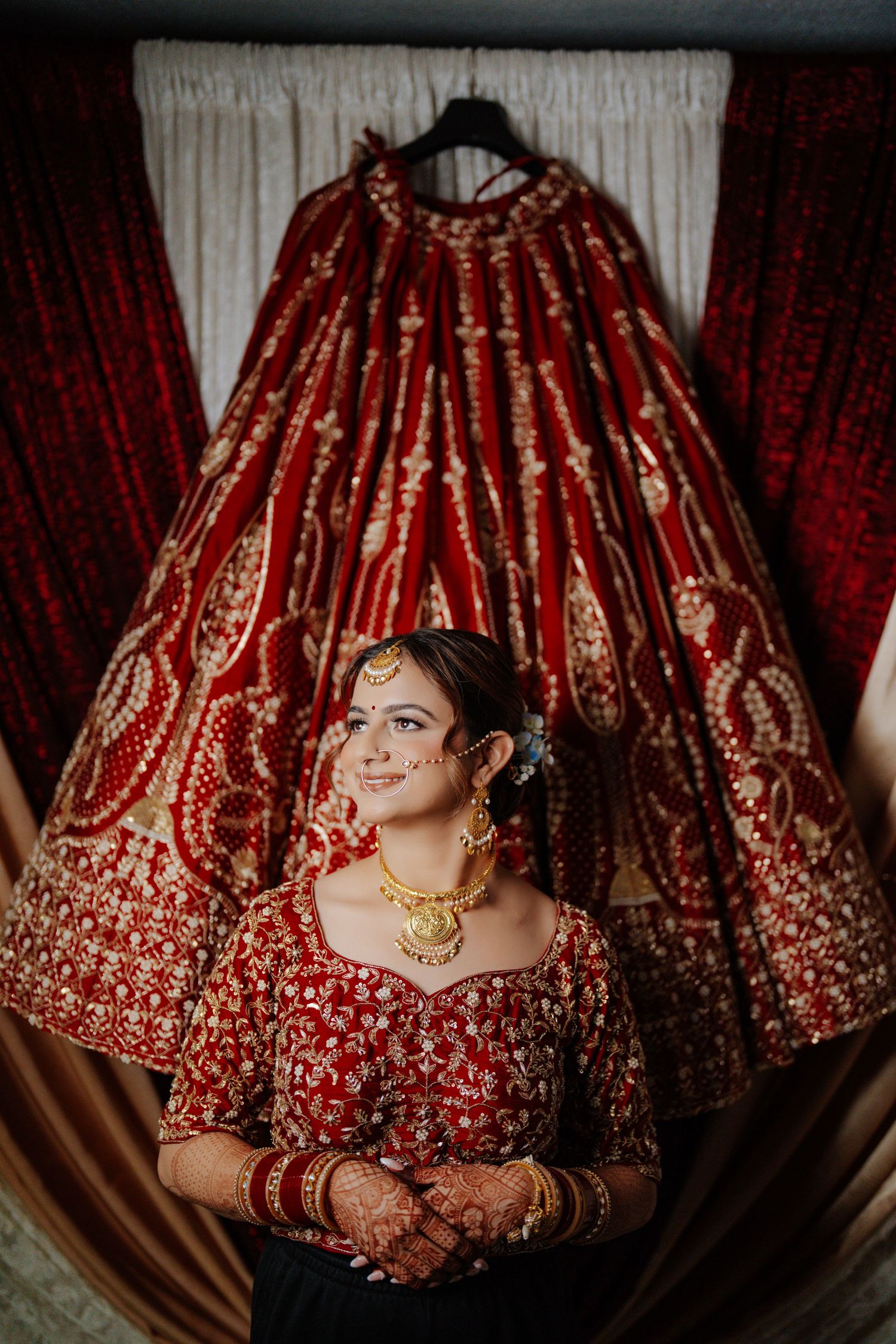 Dramatic overhead view of a red and gold embroidered bridal lehenga with detailed beadwork.