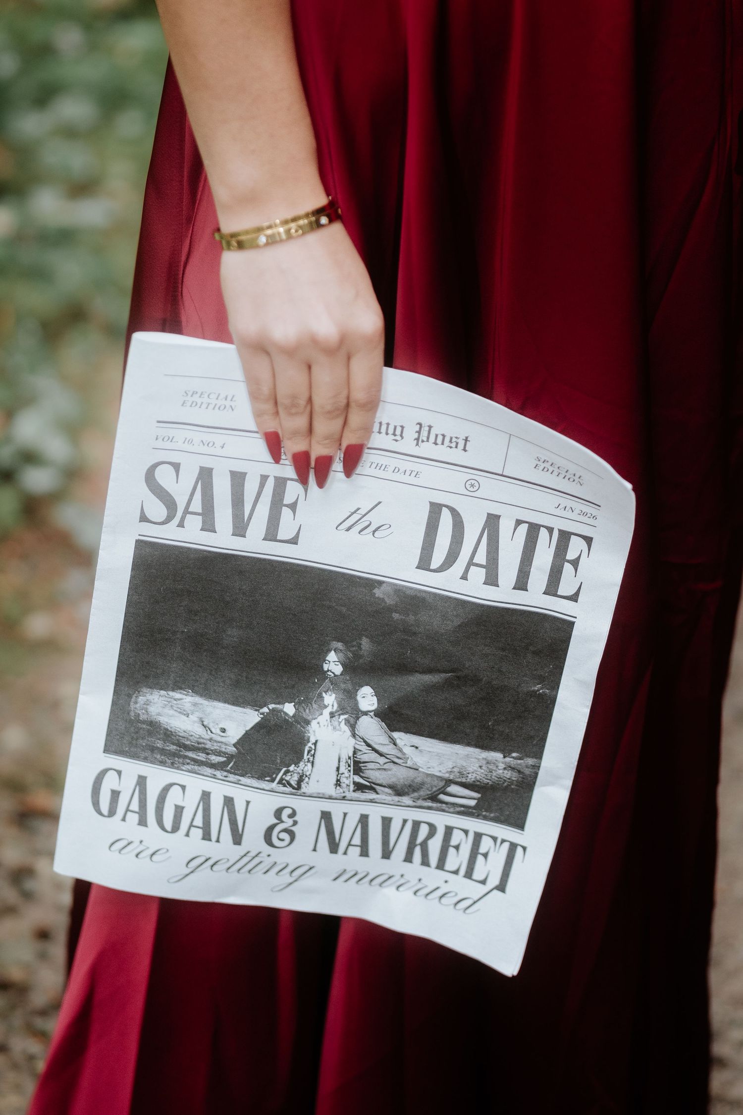 Close-up of hands holding a newspaper-style save the date announcement with black and white photo.