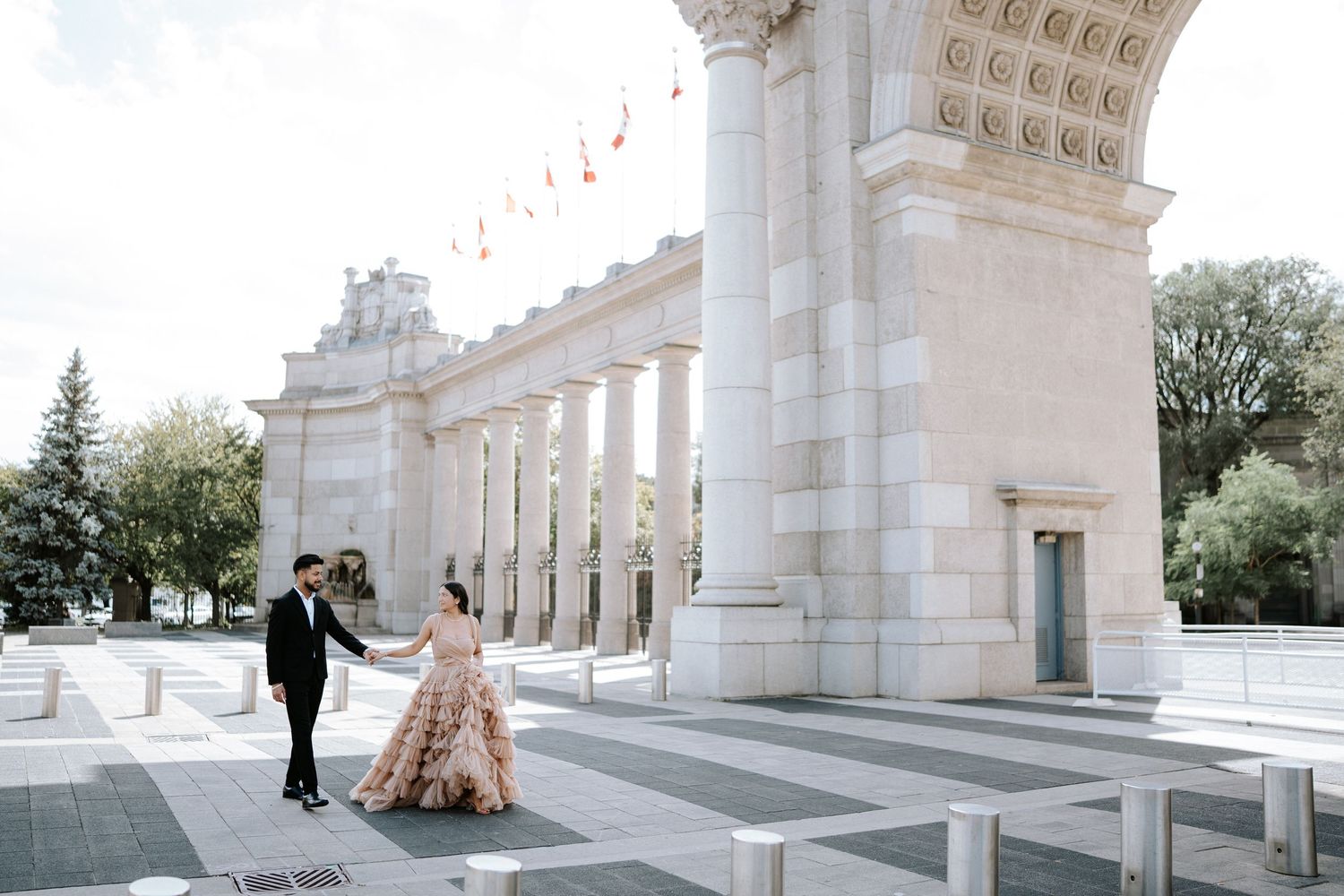 An elegant photoshoot at a grand colonnade with white pillars and ornate architecture.