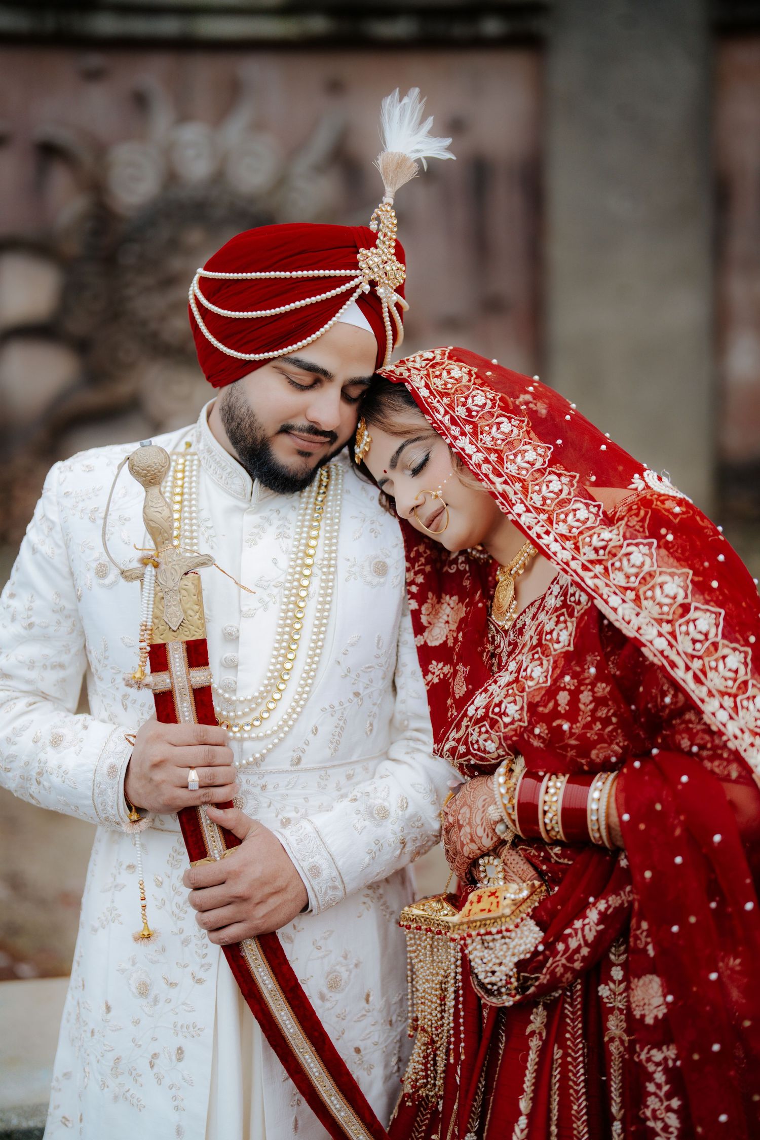 Traditional Indian wedding couple in white and red attire sharing intimate moments during their photo session.