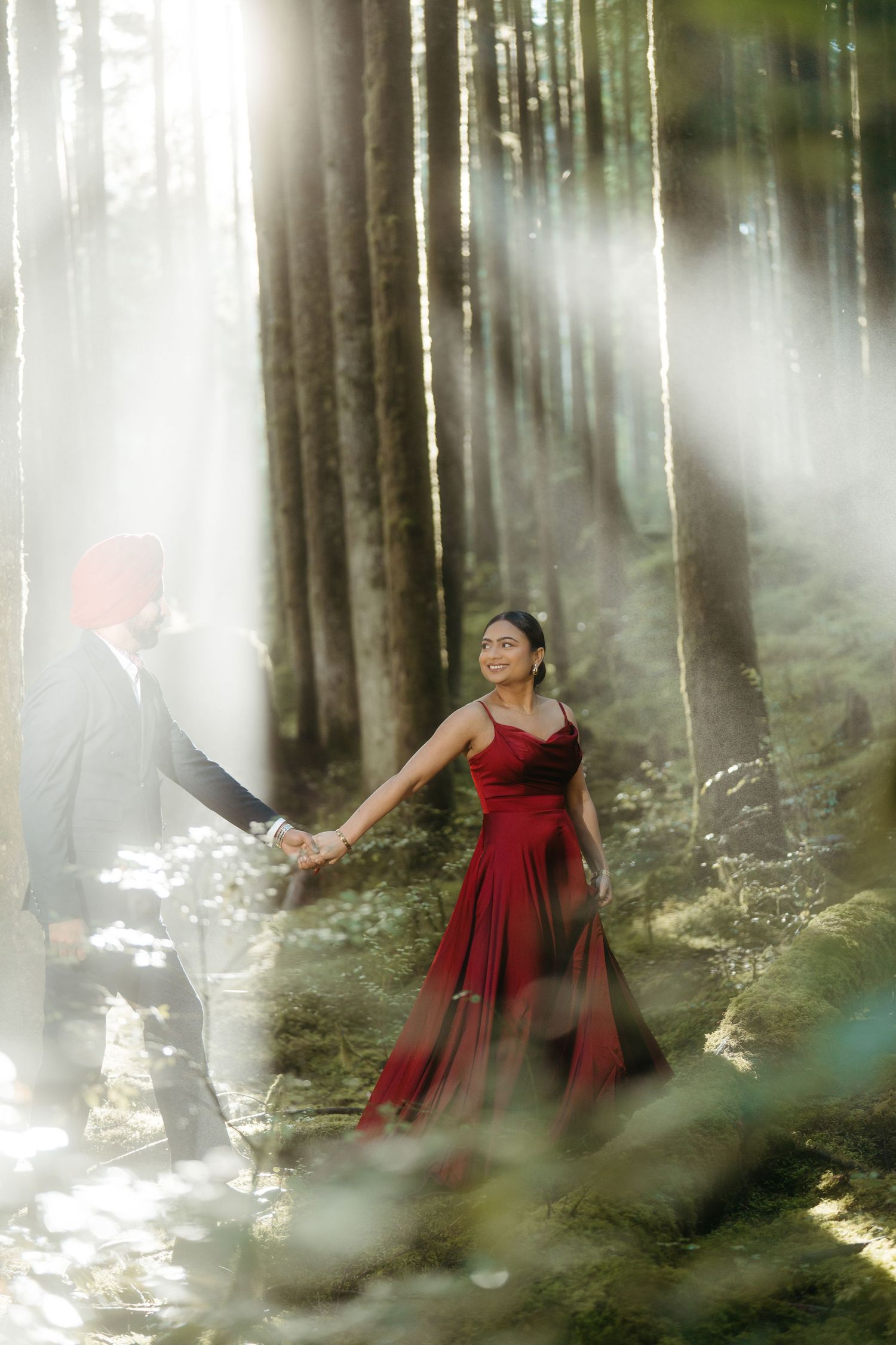 Dreamy forest photography with red dress and fog creating mystical atmosphere.