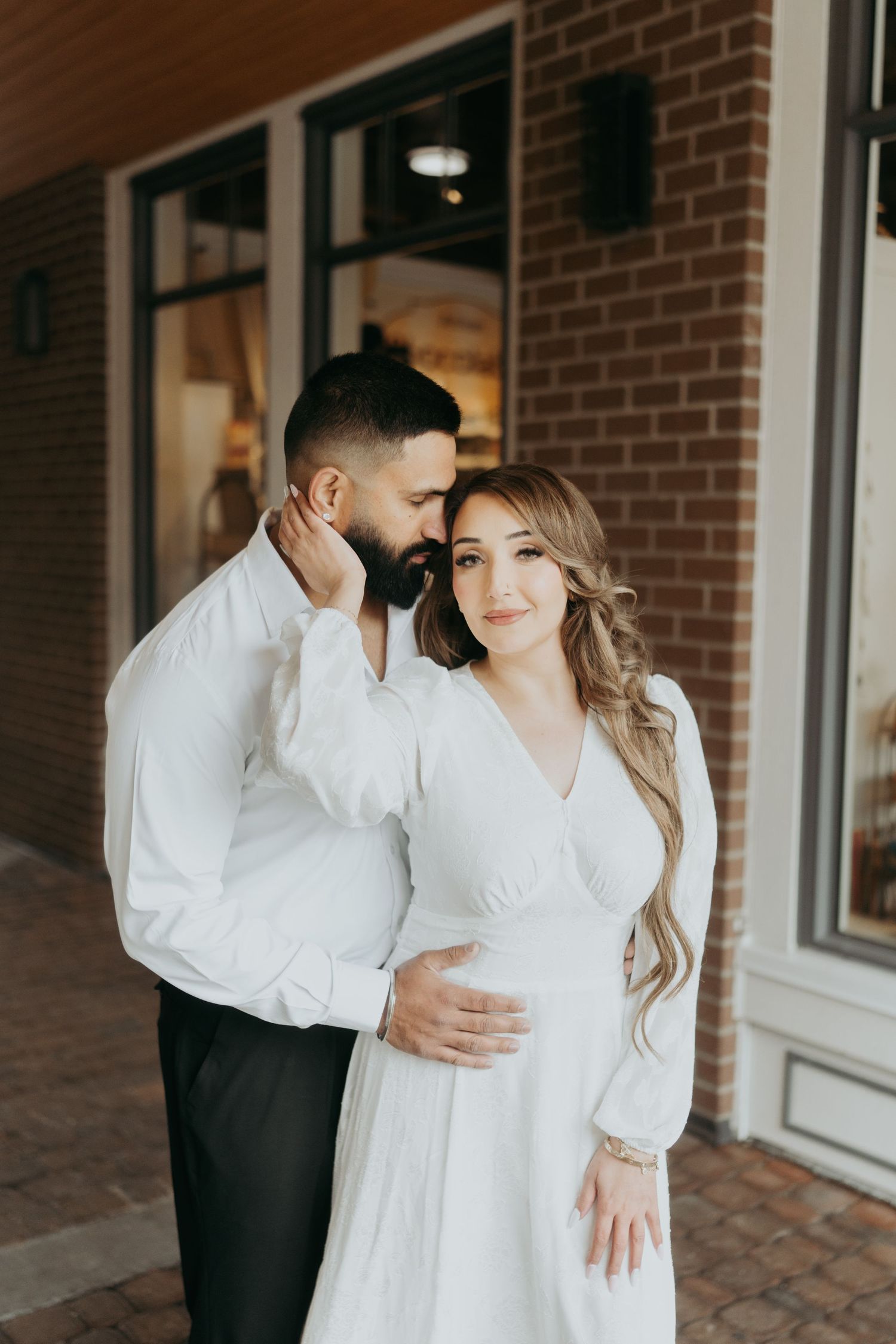 A couple in matching white outfits shares tender moments during a photoshoot.