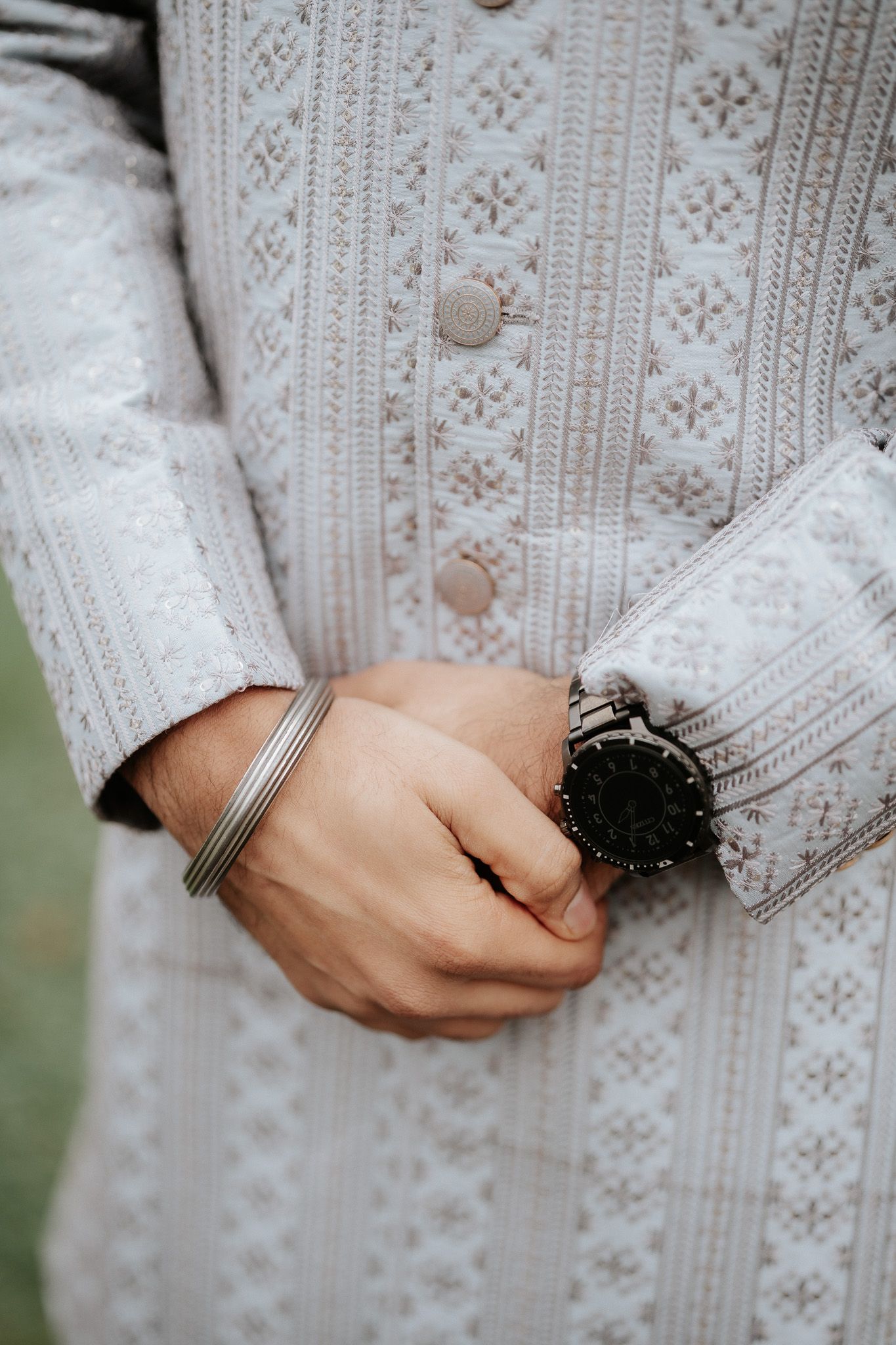 Close-up view of hands wearing delicate rings against a white lace dress sleeve.