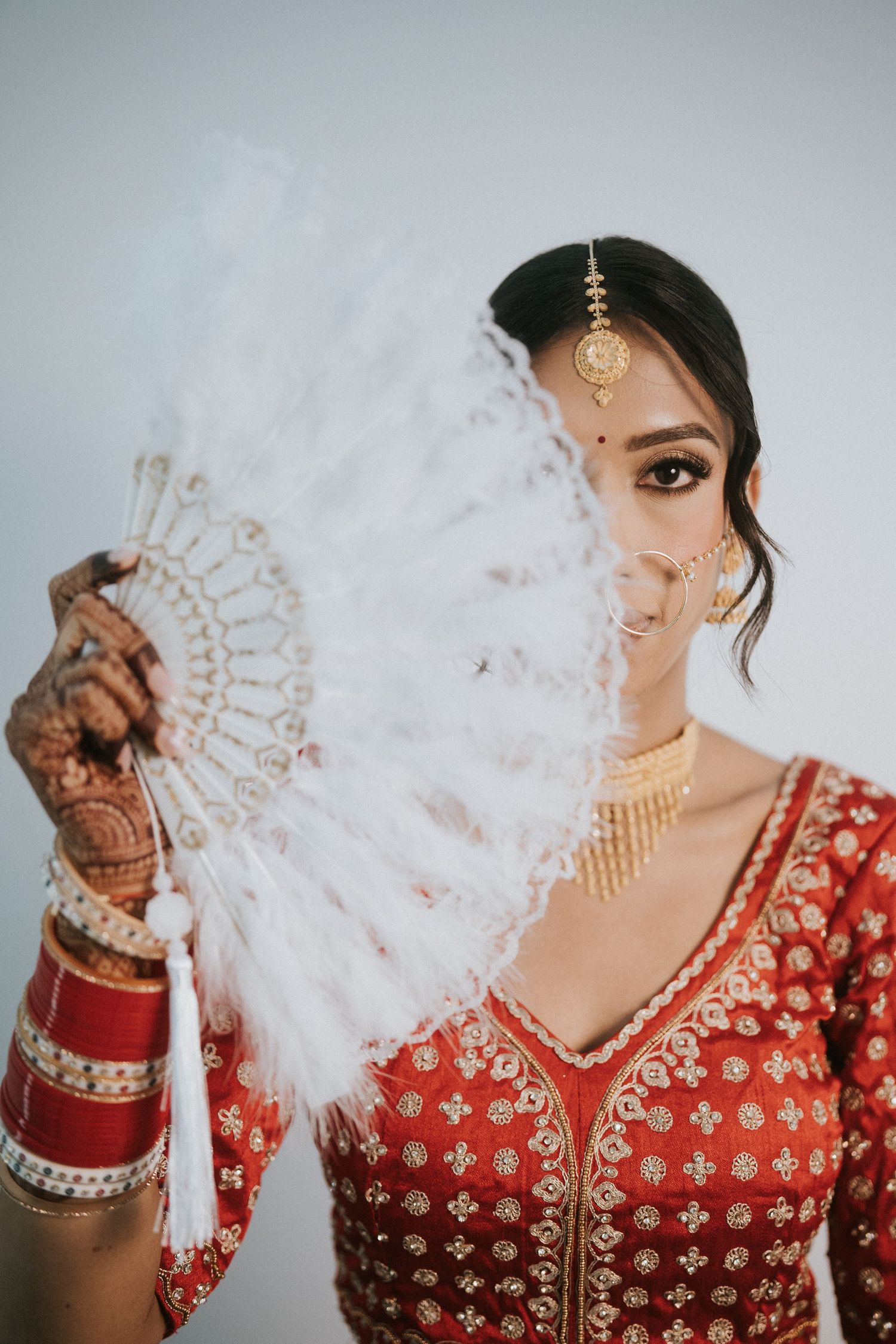 Dramatic bridal portraits featuring traditional red lehenga and mehndi-adorned hands.