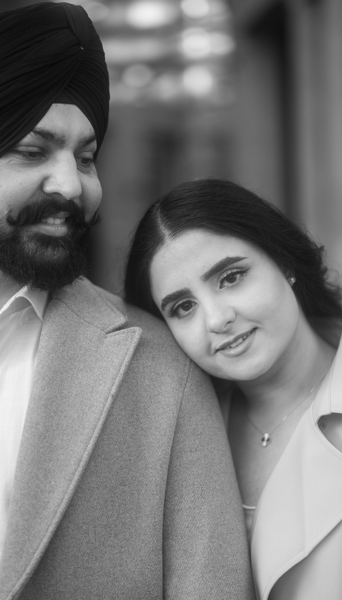 A black and white photo series showing a couple in a romantic pose with one wearing a gray coat and the other in white.