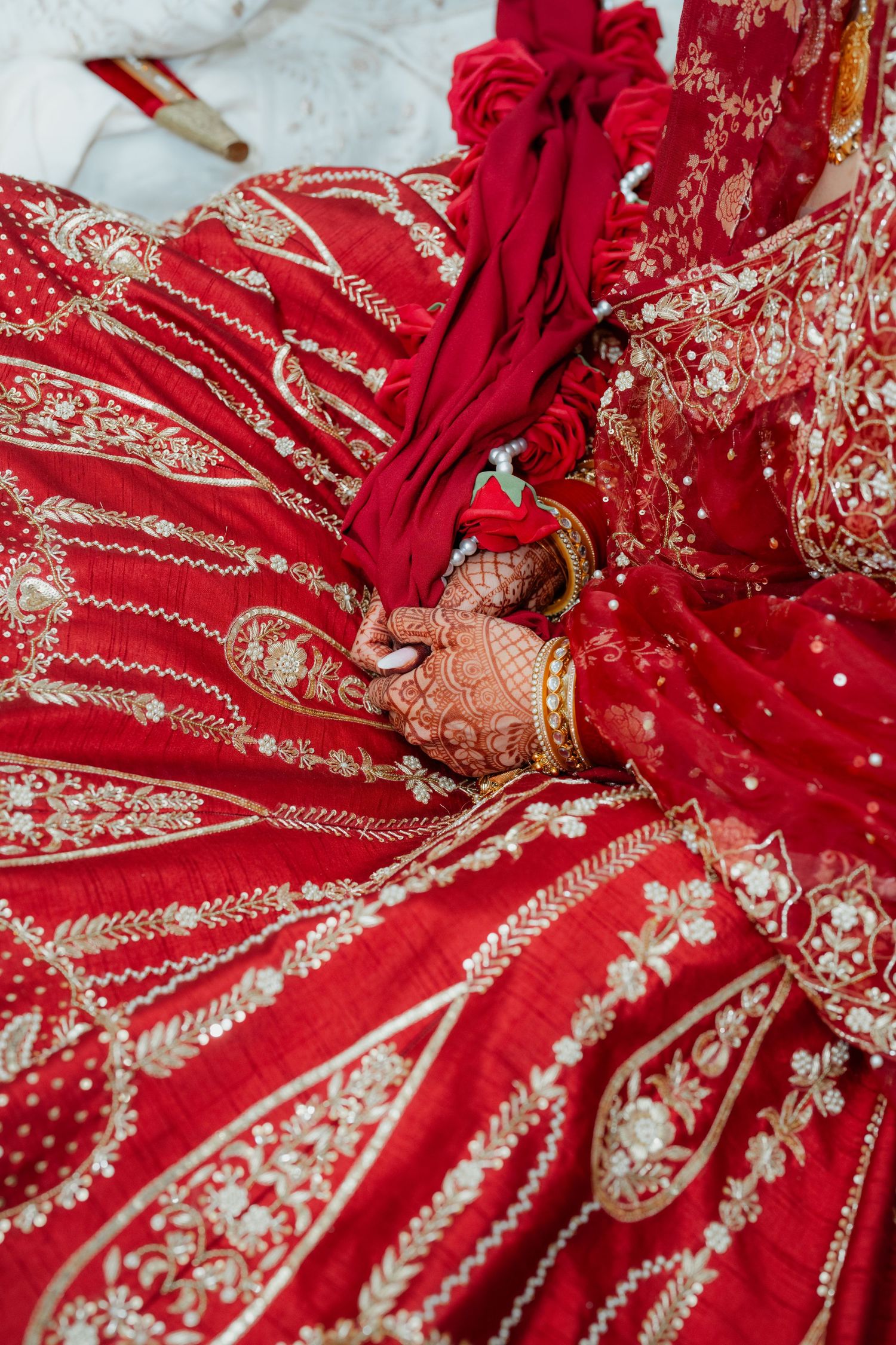 Intricate gold embroidery details on a vibrant red traditional Indian wedding lehenga with floral motifs.
