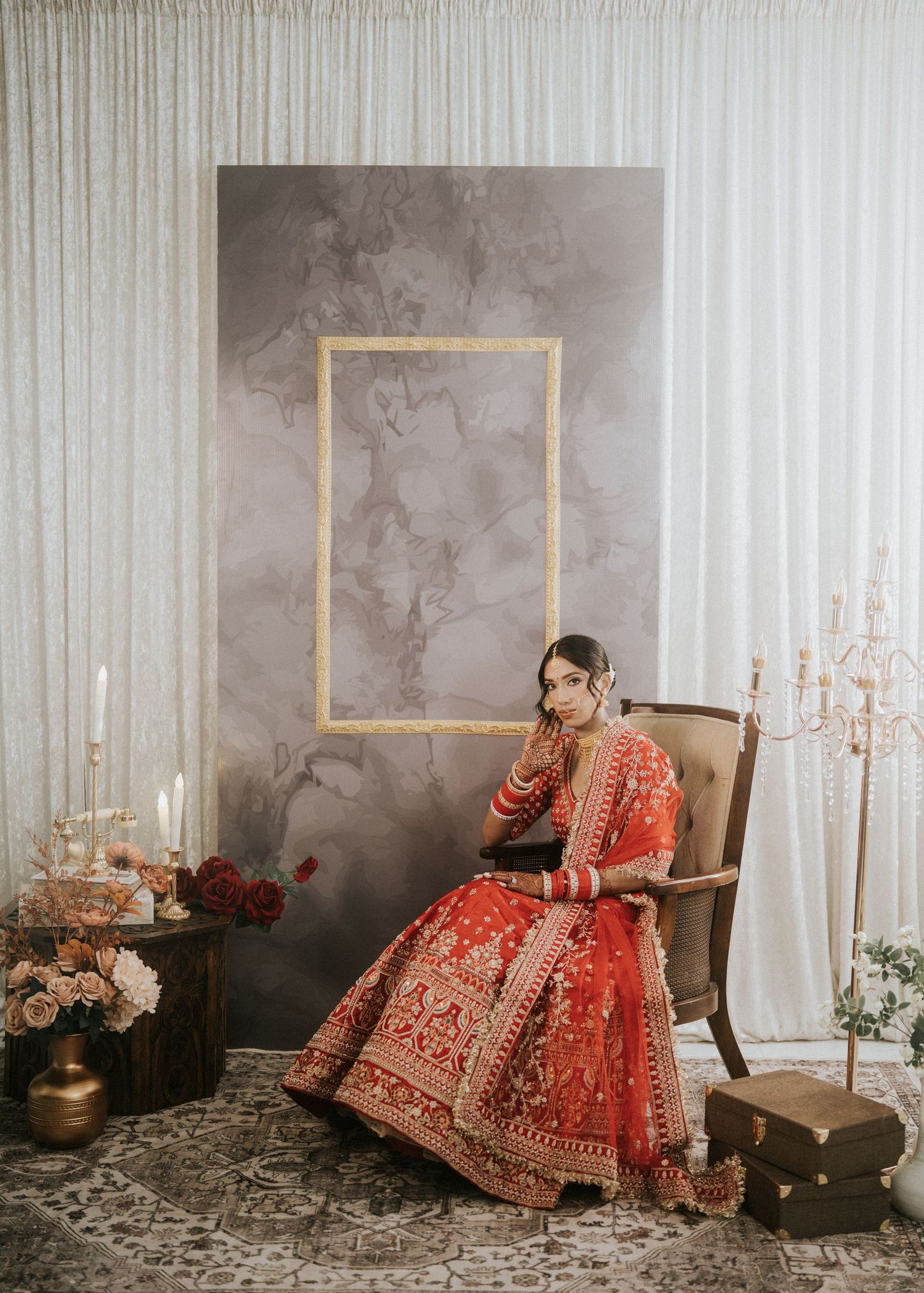 Bridal portrait session featuring a red lehenga against elegant white and grey decor with candelabras.