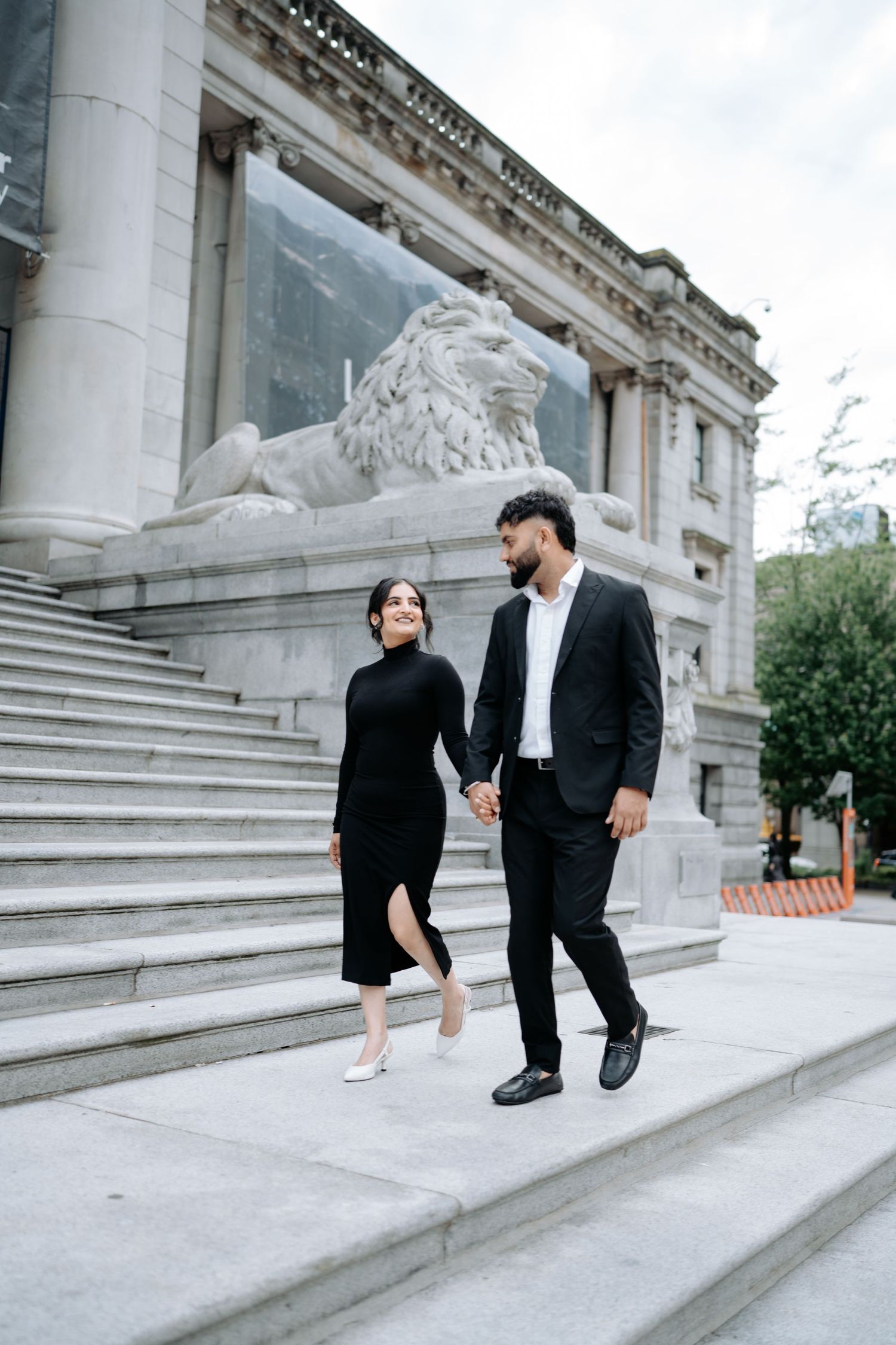 A couple interacts playfully on grand stone steps of a historic building.