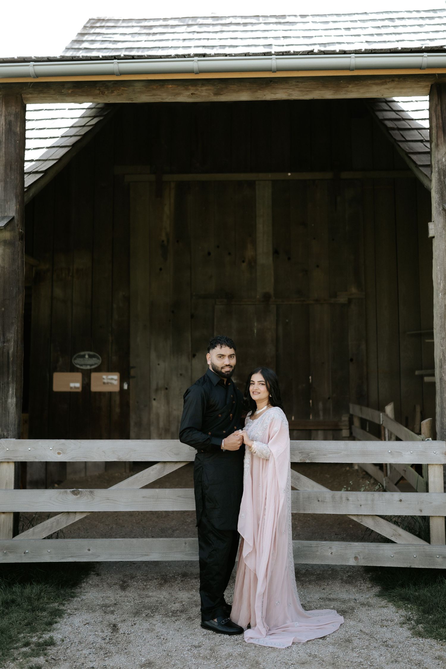 A romantic couple poses in front of a rustic wooden barn structure in a series of artistic shots.