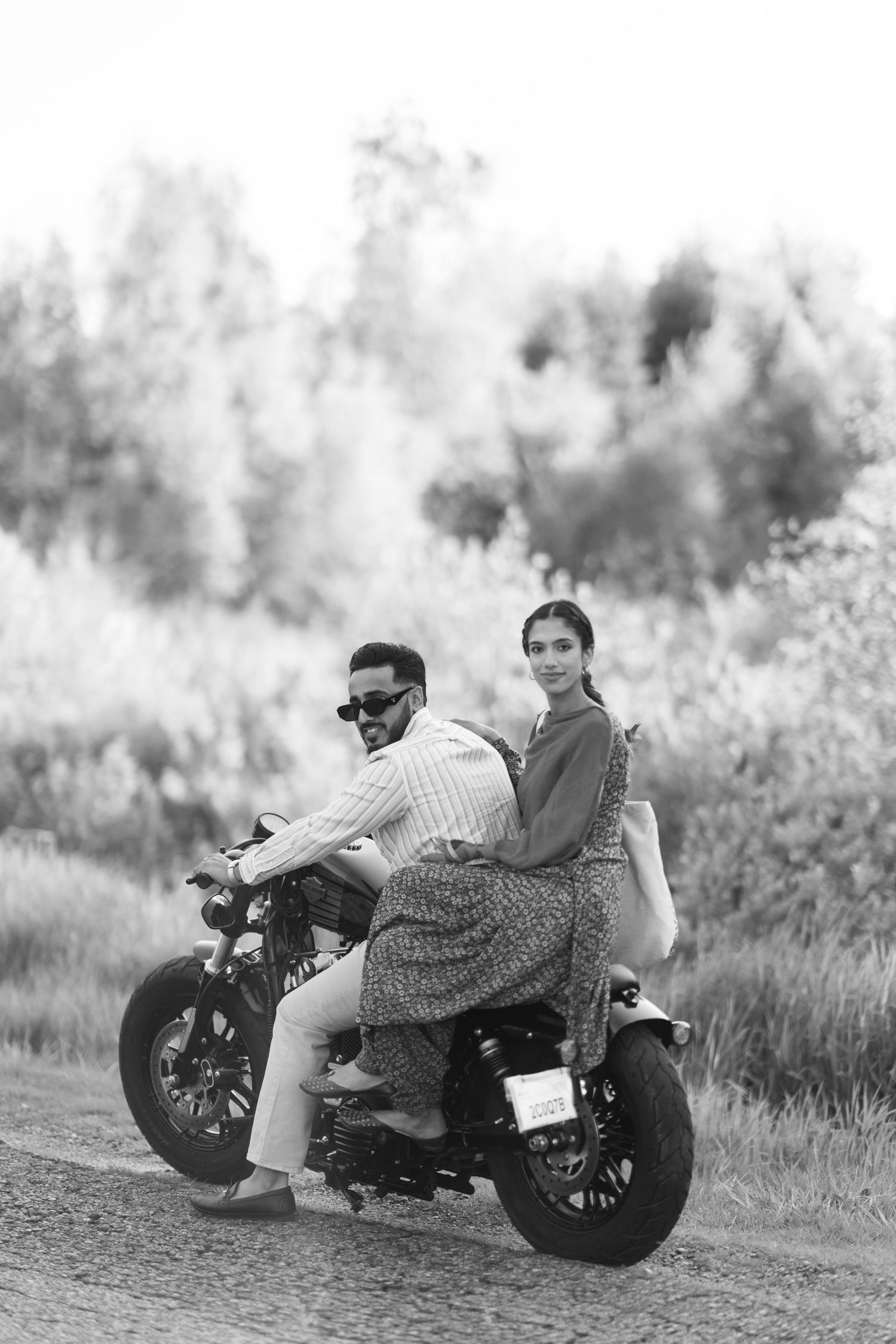 Black and white photo series of a couple sitting together on a vintage motorcycle in a grassy field.