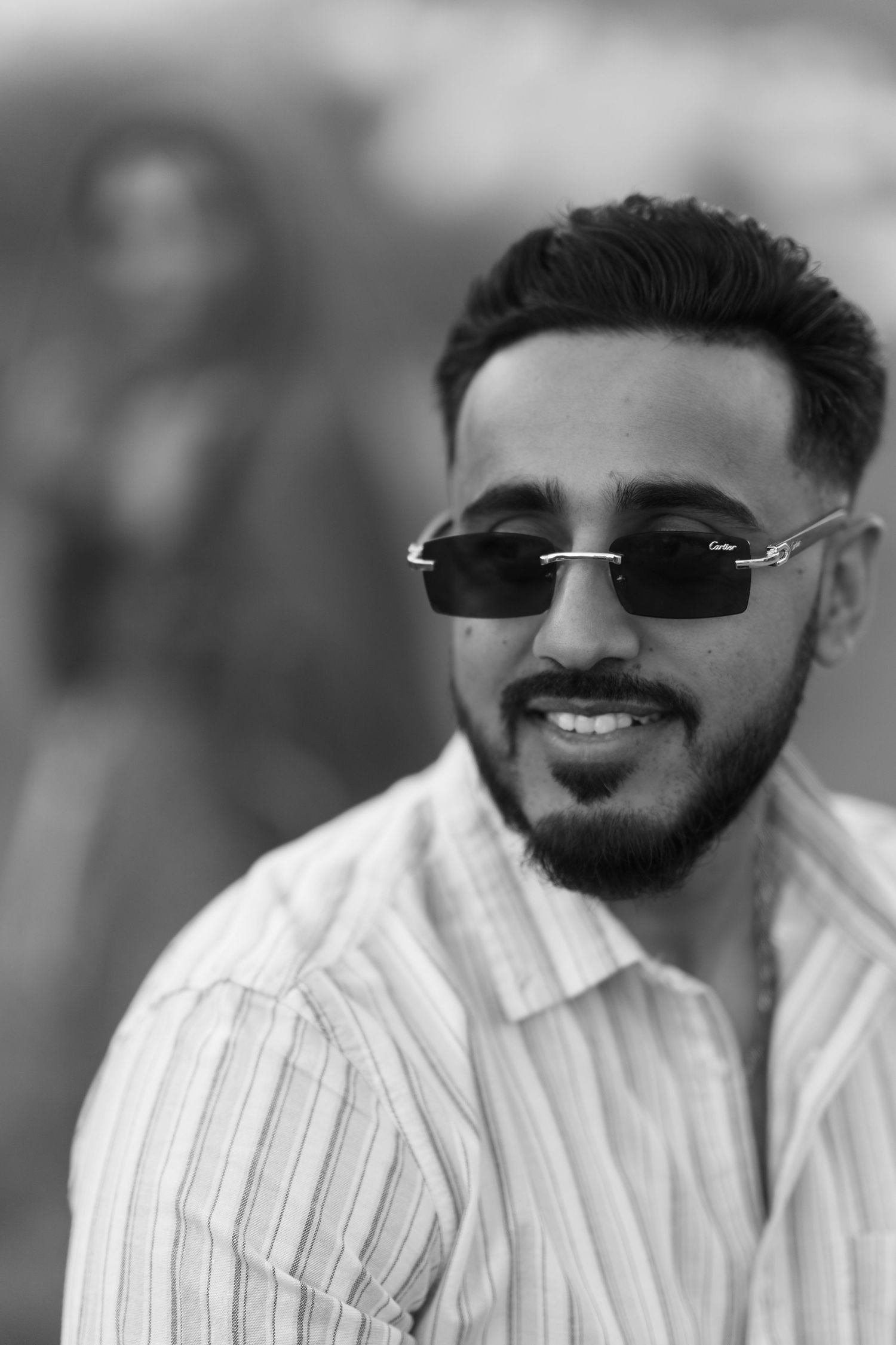 A series of black and white portrait photos showing a person wearing sunglasses and a striped shirt with a beard smiling.