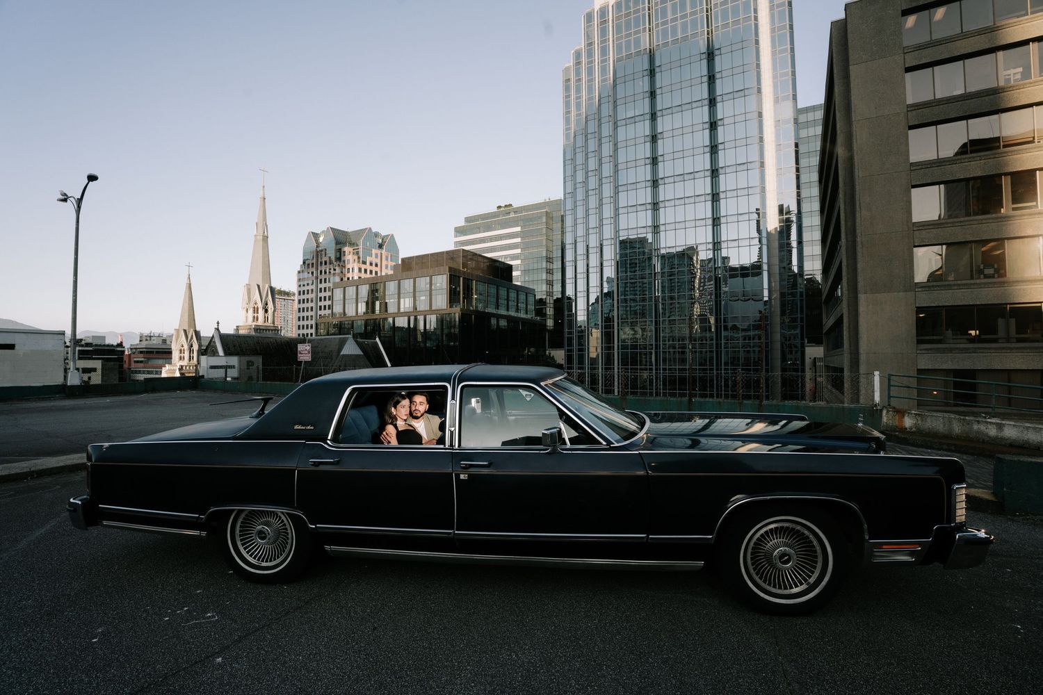 A black vintage Lincoln Continental limousine parked on a city street with buildings in the background.