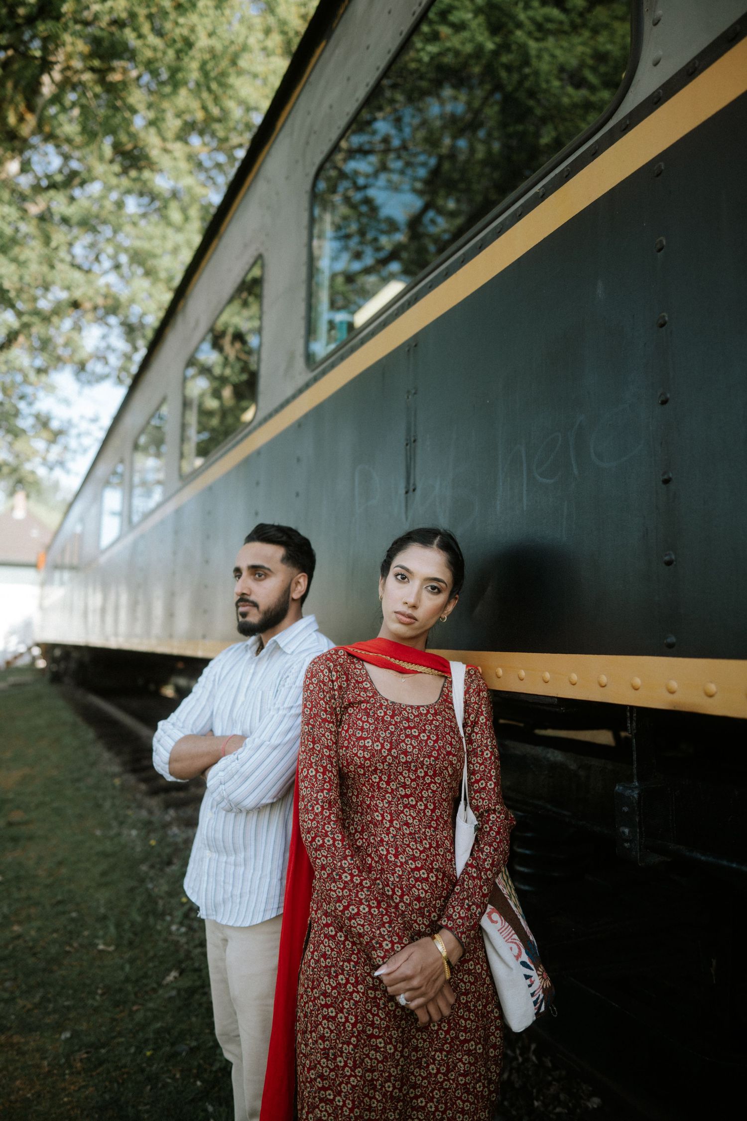 A couple poses together in traditional South Asian attire against a dark architectural backdrop.