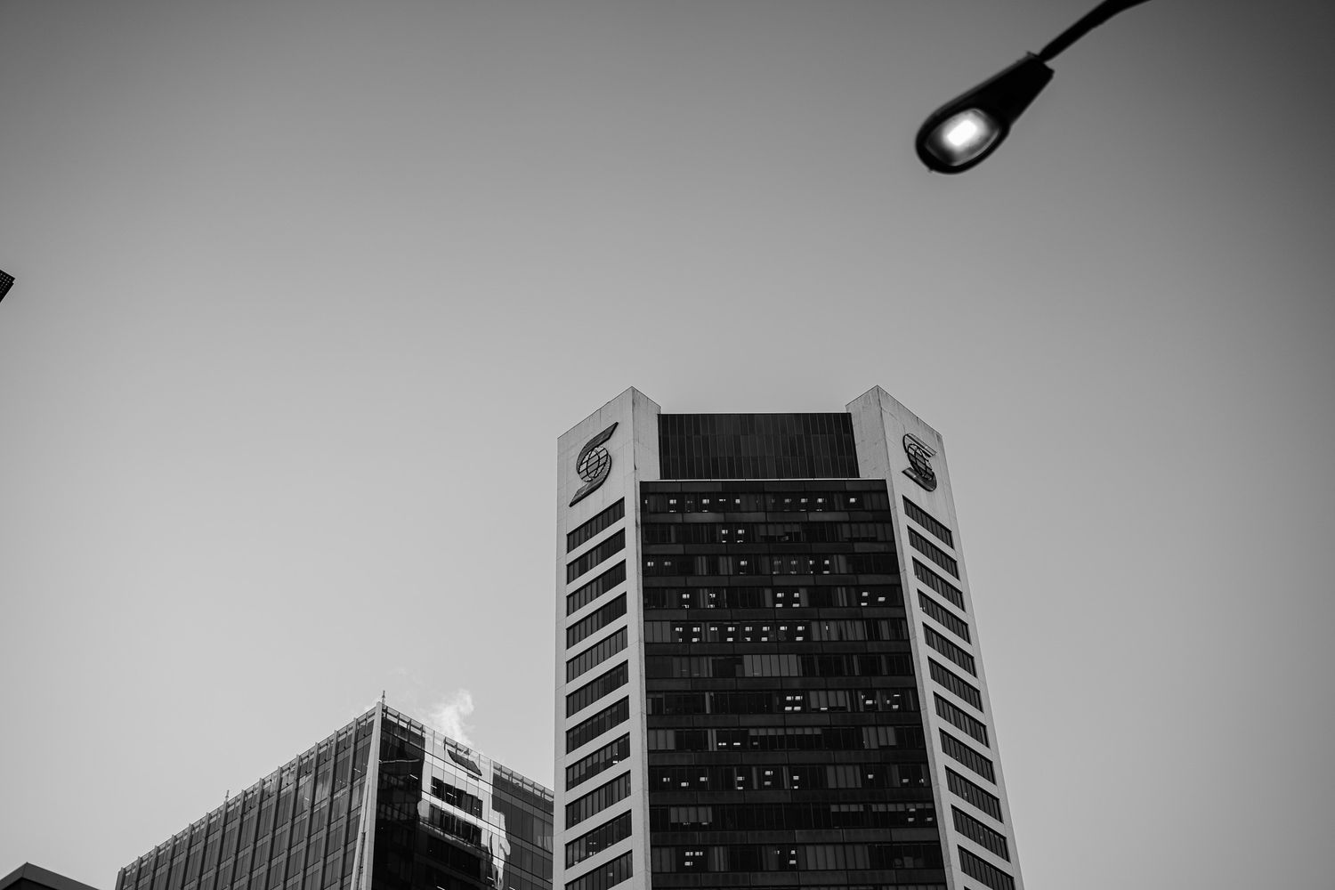 Modern office buildings with dark glass facades photographed from a low angle against a cloudy sky.
