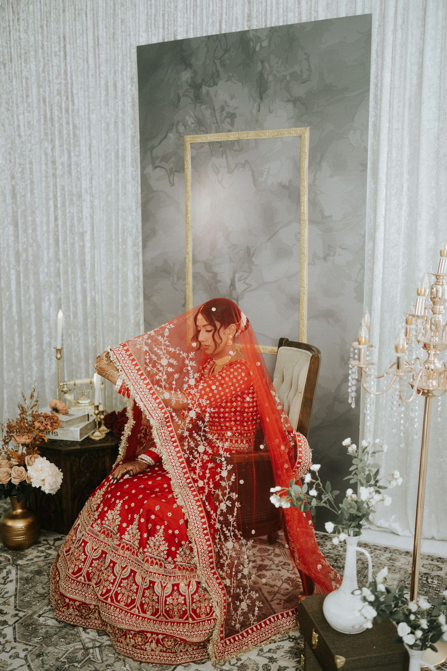 Traditional red Indian bridal lehenga displayed on mannequins with intricate gold embroidery and floral decorations.