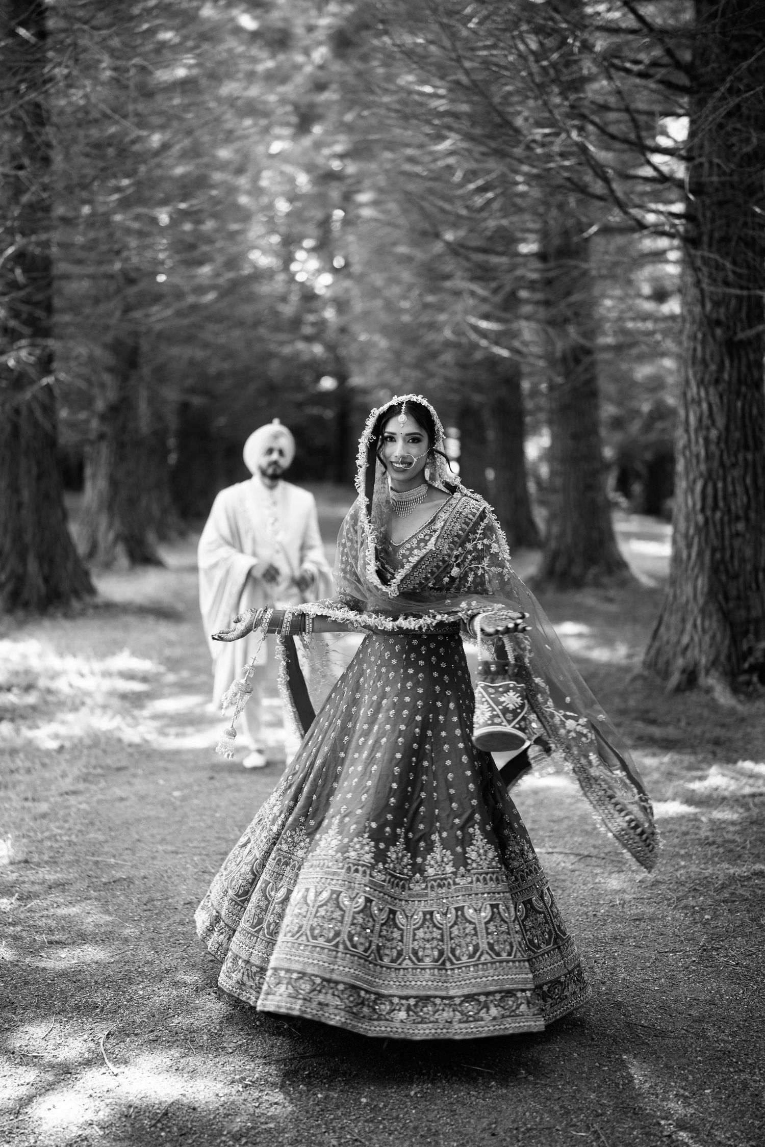 Black and white wedding photography sequence in a pine forest with traditional Indian attire.