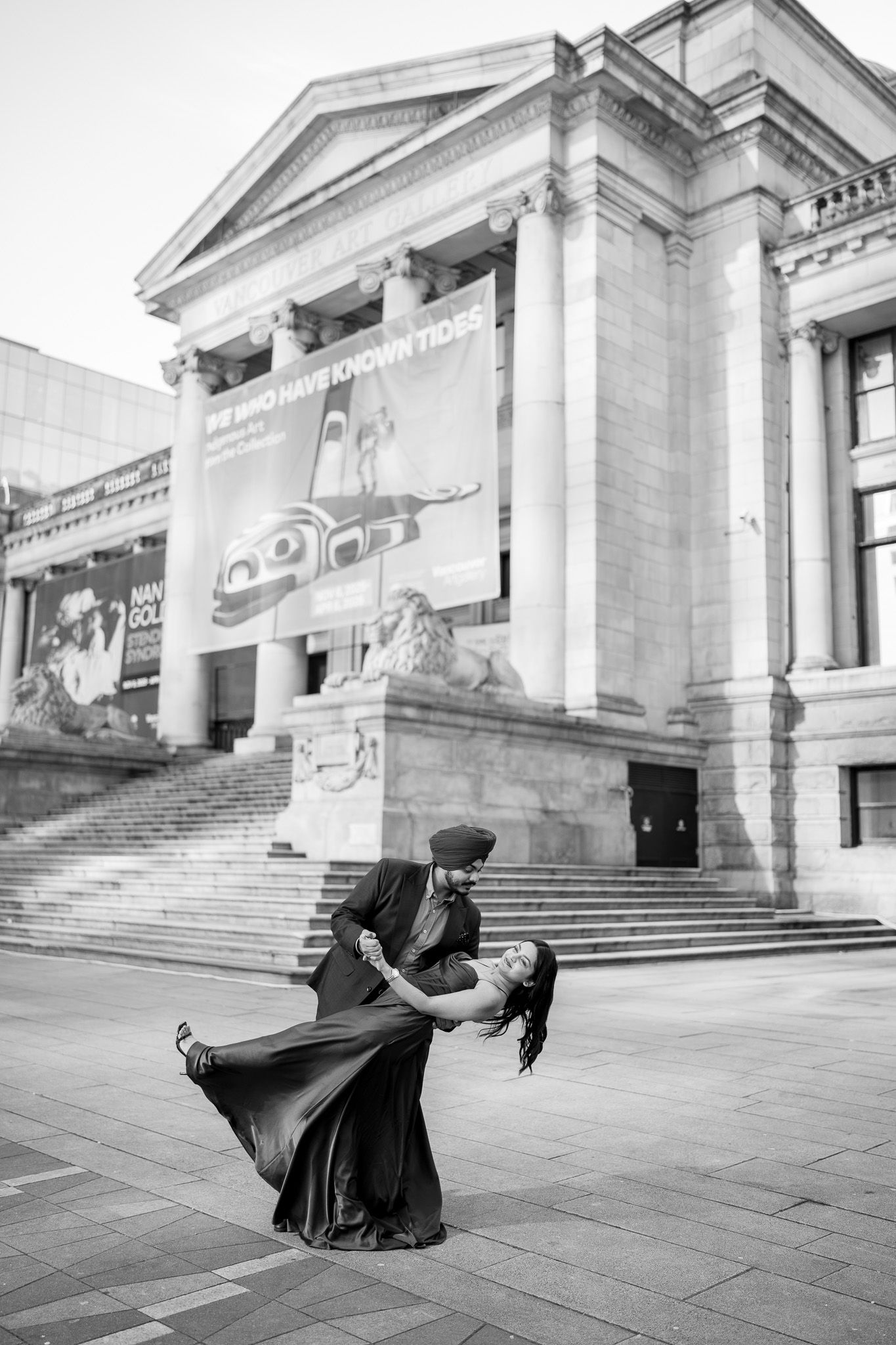 A sequence of artistic dance movements captured in black and white against a grand architectural backdrop with stone steps.