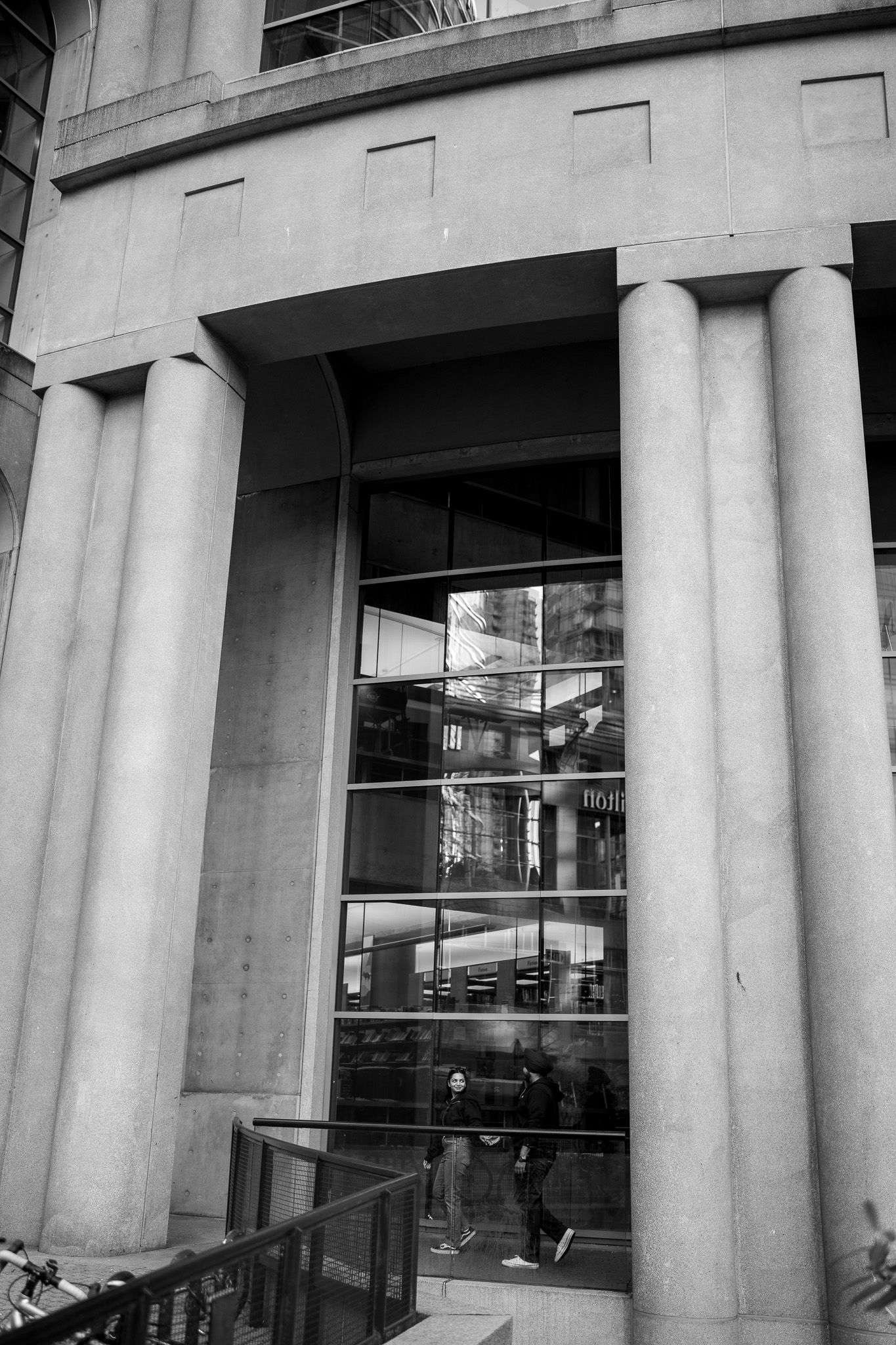 Modern building exterior with white columns and glass windows creating an architectural pattern.