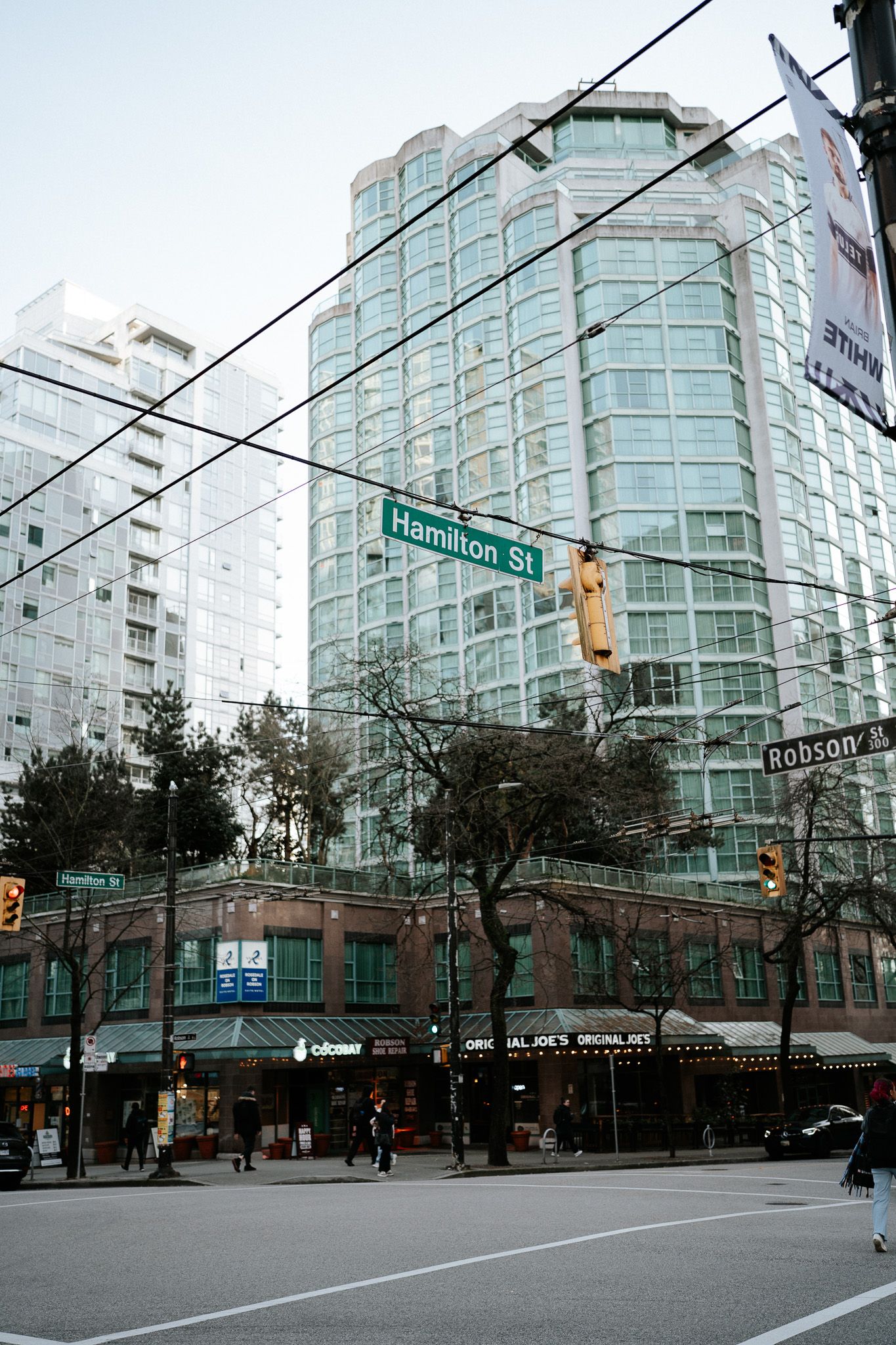 Modern glass high-rise buildings line an urban intersection with Hamilton Street sign visible in Vancouver.