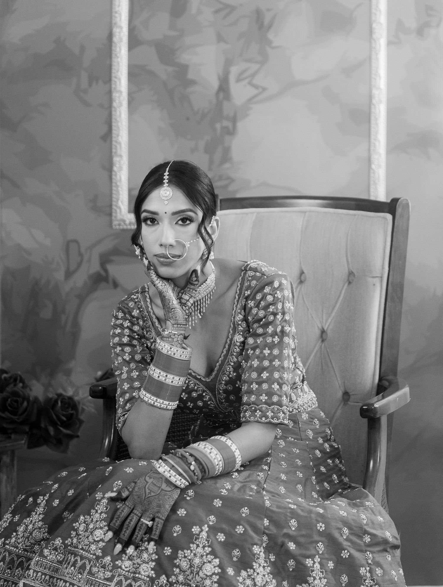 Black and white portraits of bride in traditional attire seated in an elegant chair.