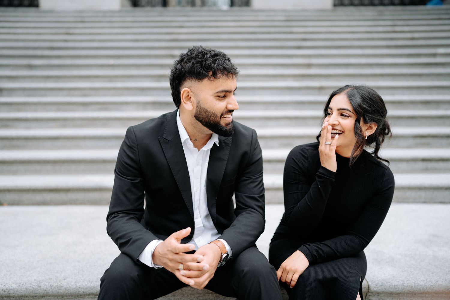 A couple engages in intimate conversation while seated on concrete steps.