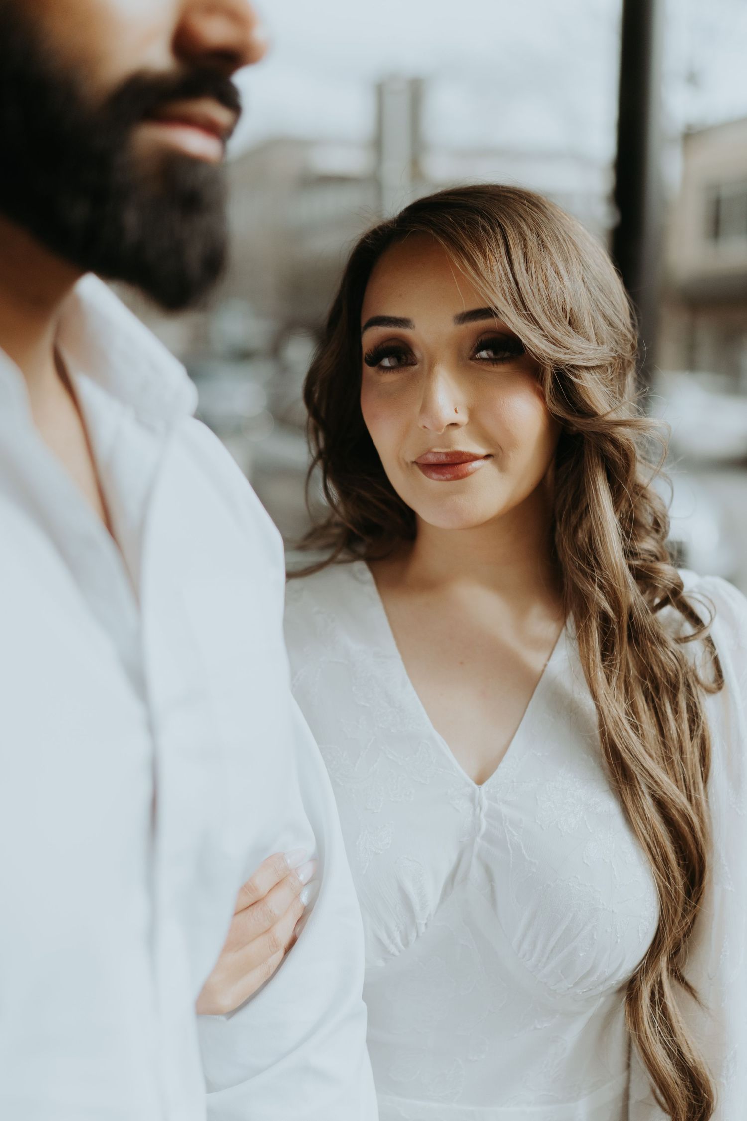 A close-up portrait of a couple in white clothing with soft, romantic lighting.