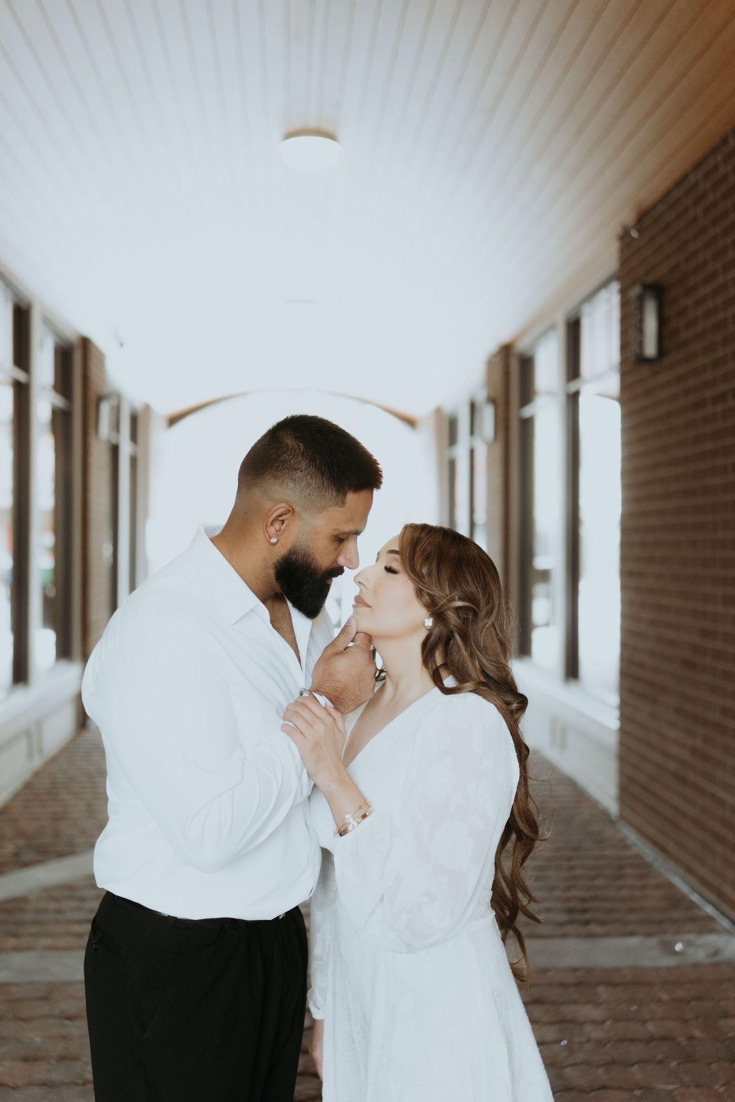 Intimate couple moments captured in sequence along a brick-lined hallway.