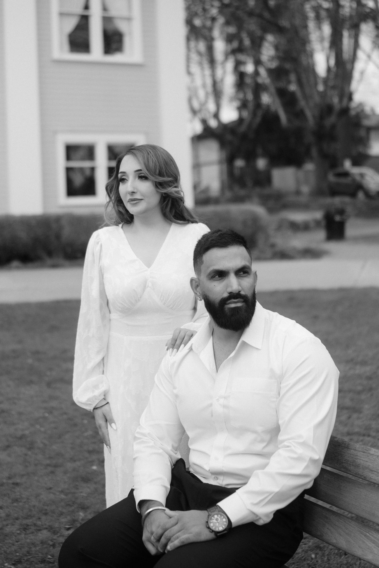 A black and white portrait of a couple sitting on a wooden bench.
