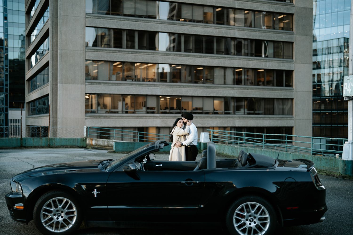 A black convertible BMW M3 parked on a city street with modern glass buildings in the background.