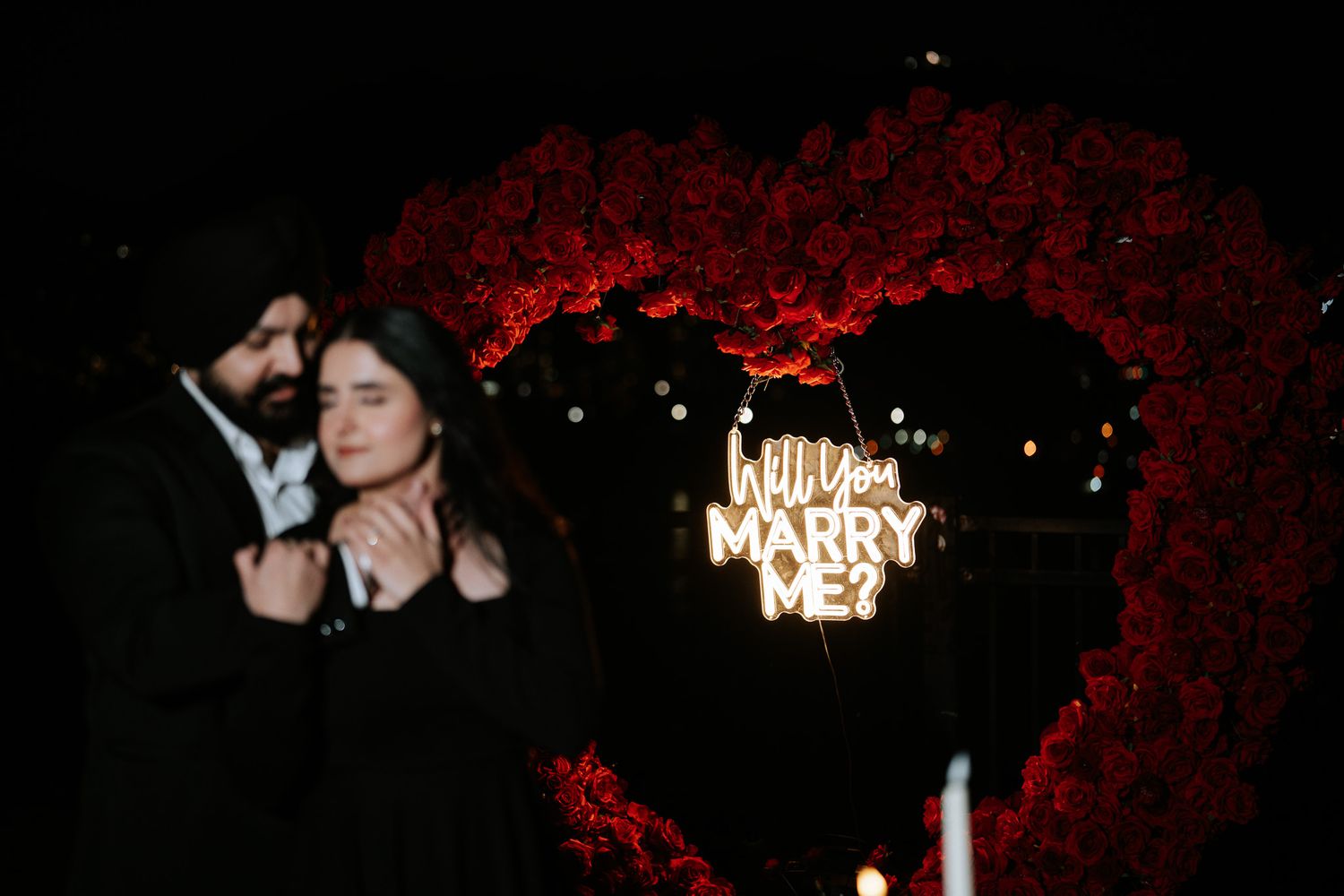 A series of dark nighttime photos showing illuminated 'MARRY ME' letters arranged for a romantic proposal.