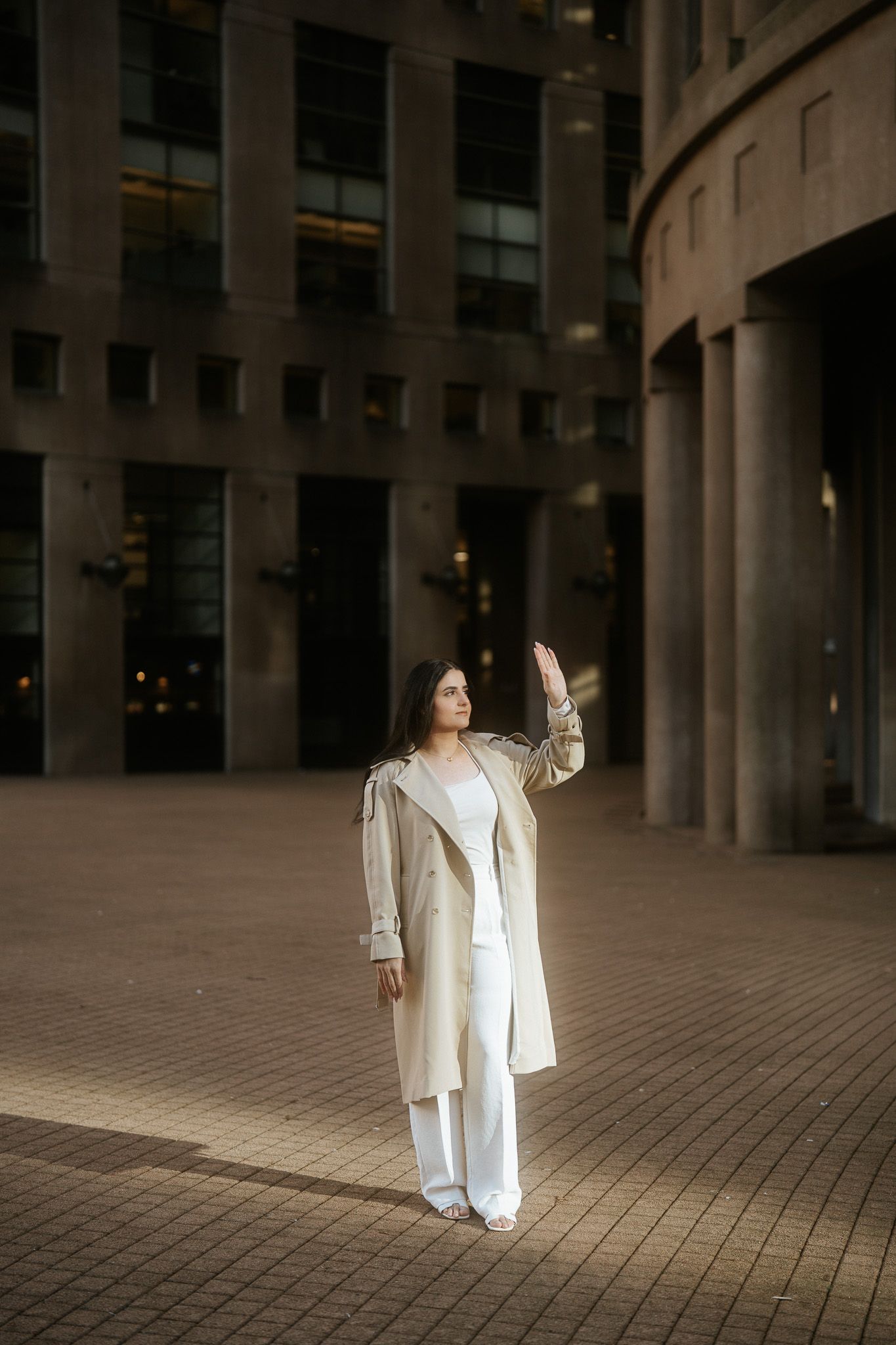 A person in a flowing white outfit stands in an elegant columned courtyard at dusk creating a dramatic silhouette.