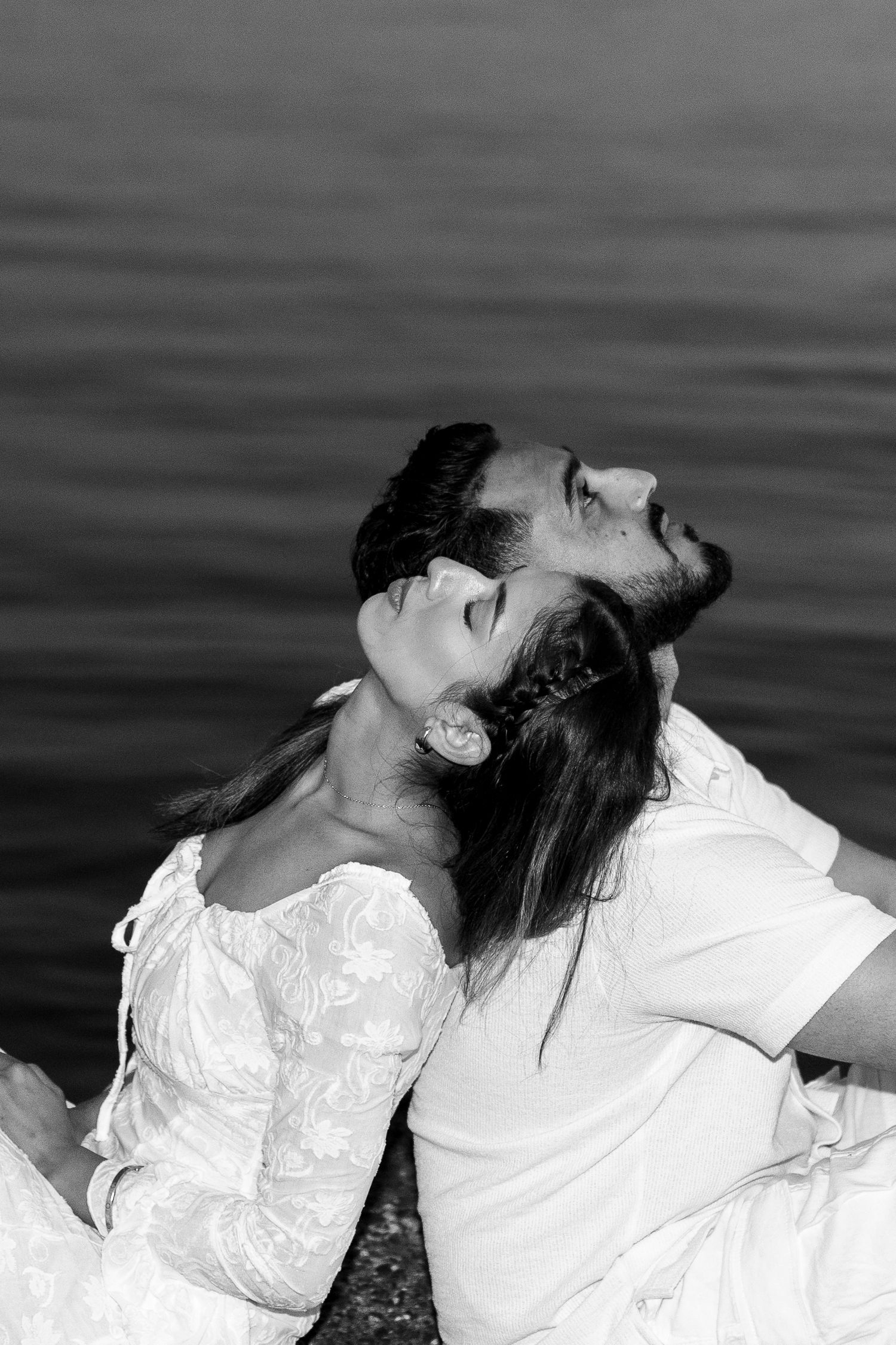 A romantic black and white photo sequence showing a couple in white clothing leaning back over water.