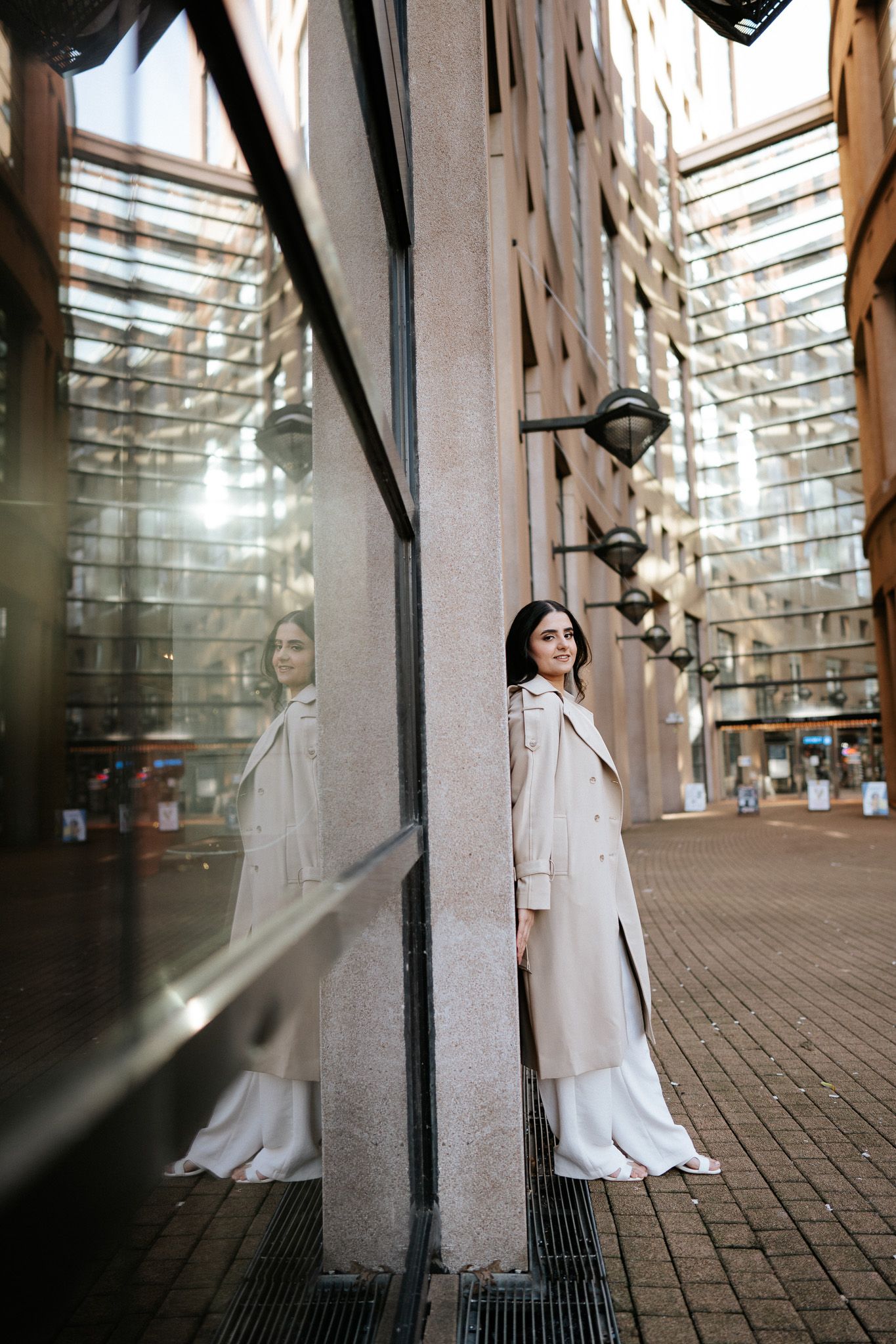 A person in a flowing white dress stands in a brick-lined tunnel with dramatic lighting and shadows.