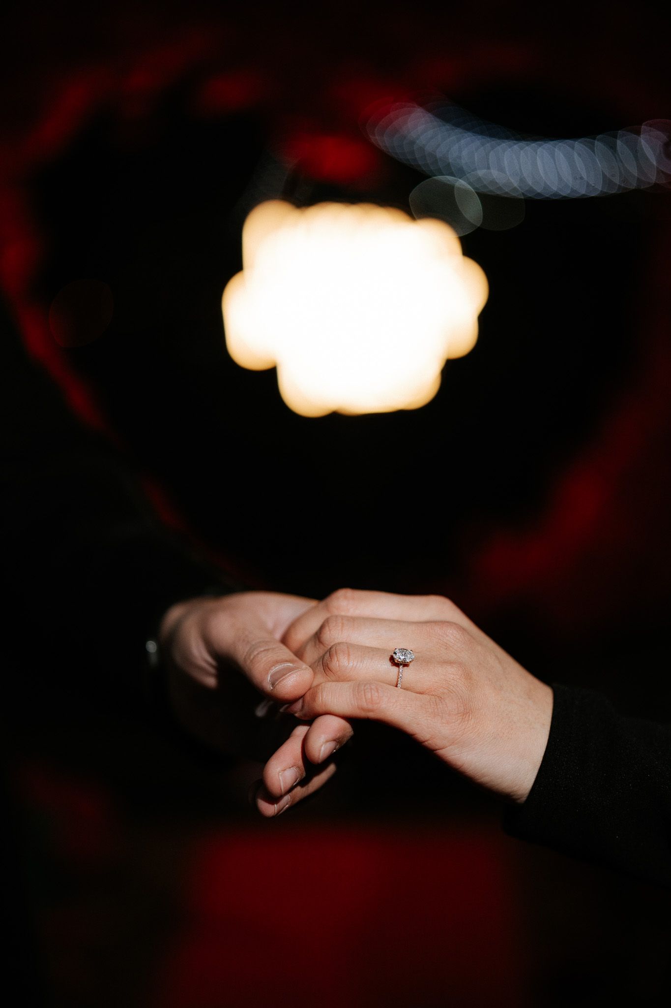 A close-up sequence of hands exchanging a diamond ring in a dark setting with dramatic lighting.