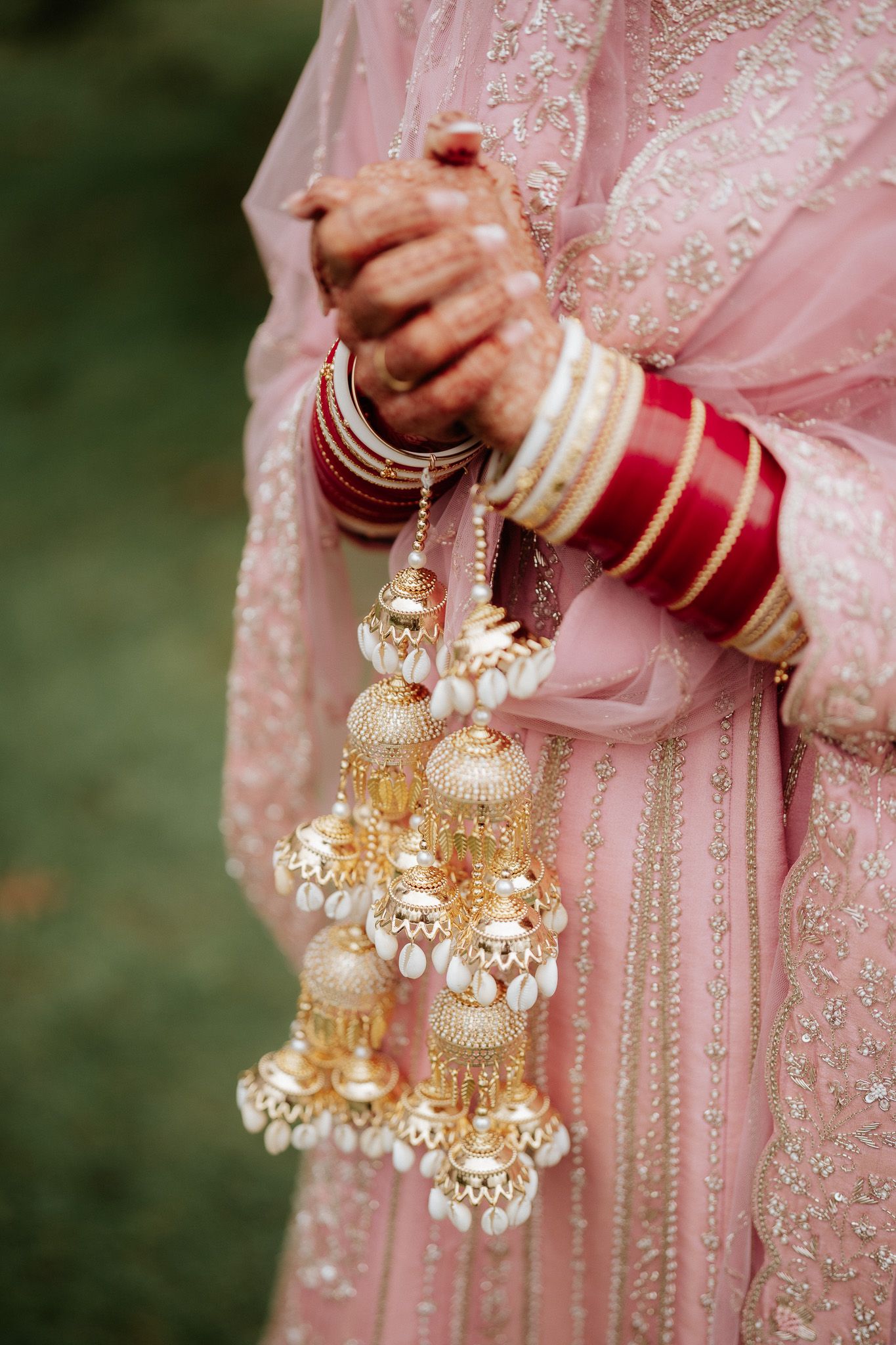 Traditional Indian wedding kalire jewelry in gold with white pearls and beads hanging from pink attire.