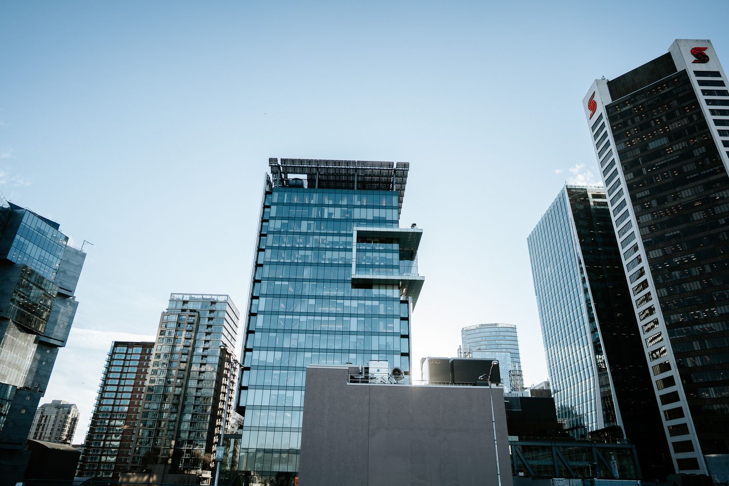 Modern glass skyscrapers and office buildings line an urban street in a bustling downtown business district.