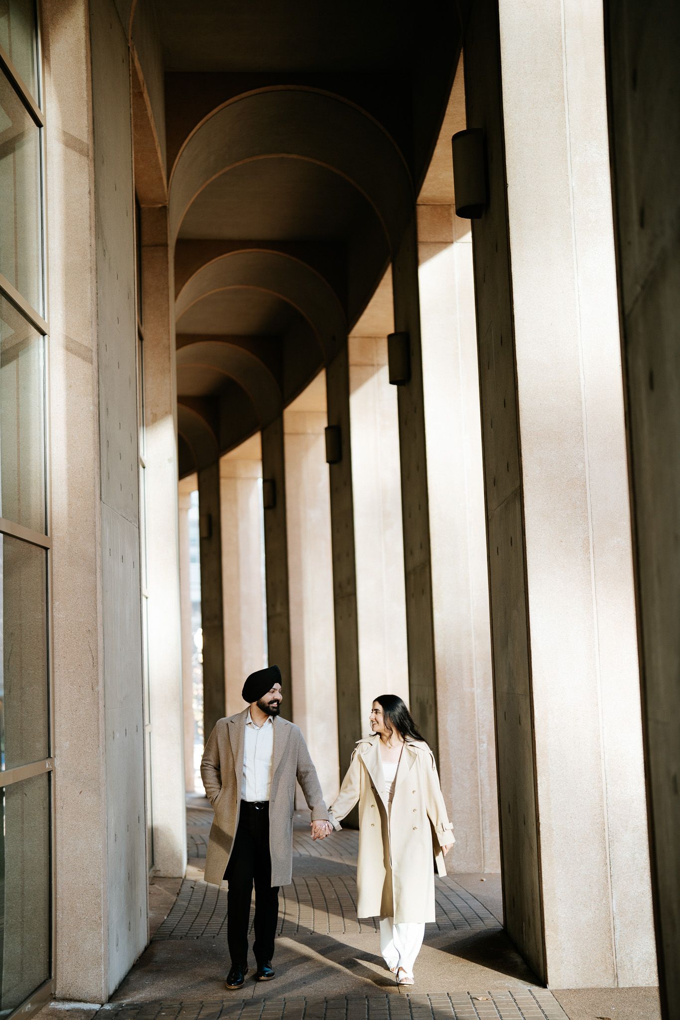 Architectural interior with repeating white columns creating a curved corridor with dramatic shadows and light.