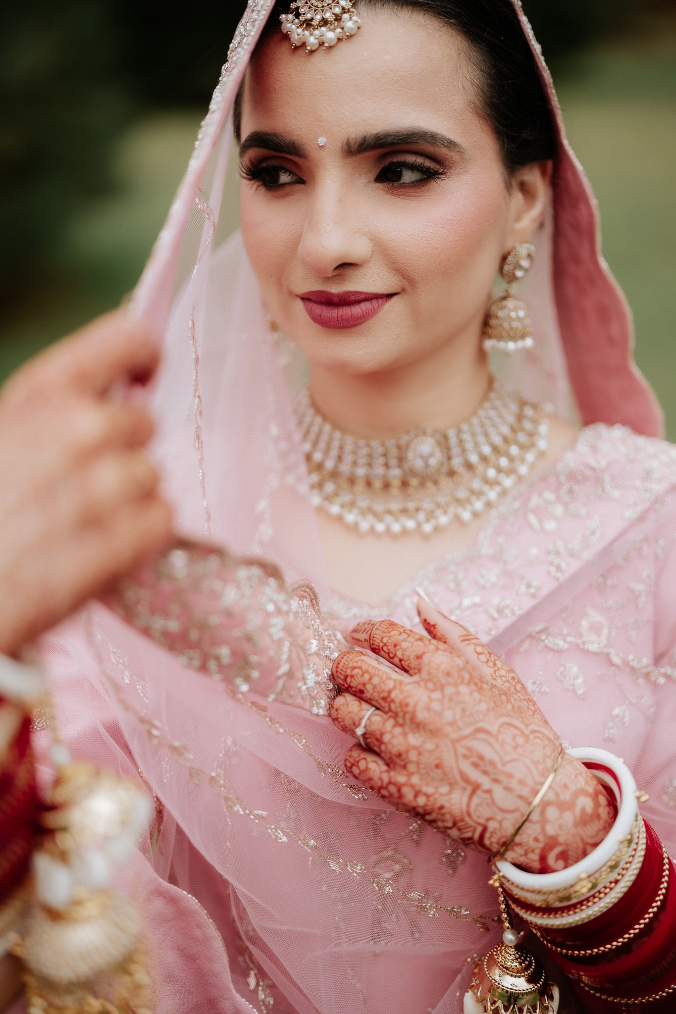 A series of close-up shots showing traditional Indian bridal details with pink attire, henna designs and pearl jewelry.