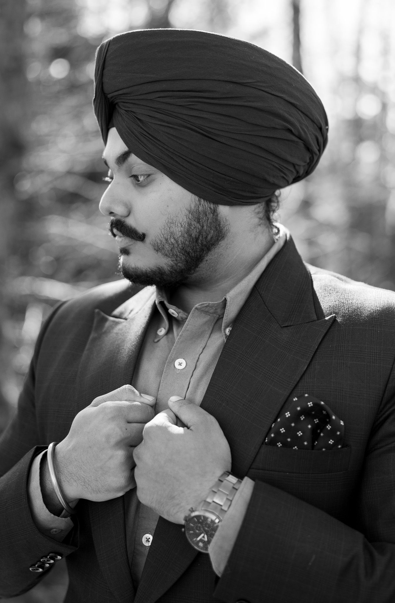 Black and white portrait series showing a person in a turban and suit adjusting their collar in four poses.