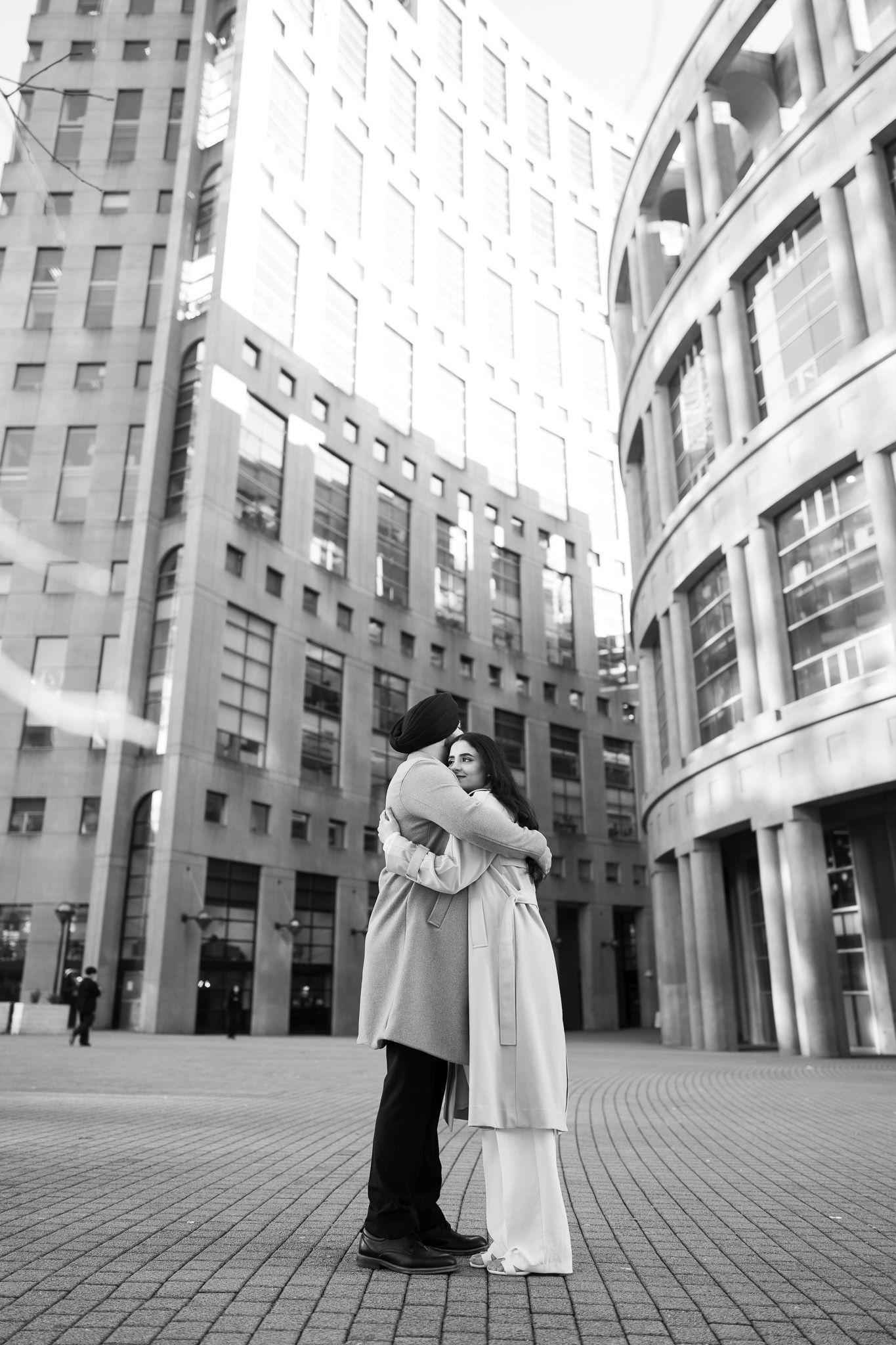 A sequence of black and white photos showing two figures in flowing garments interacting in front of a modern building.