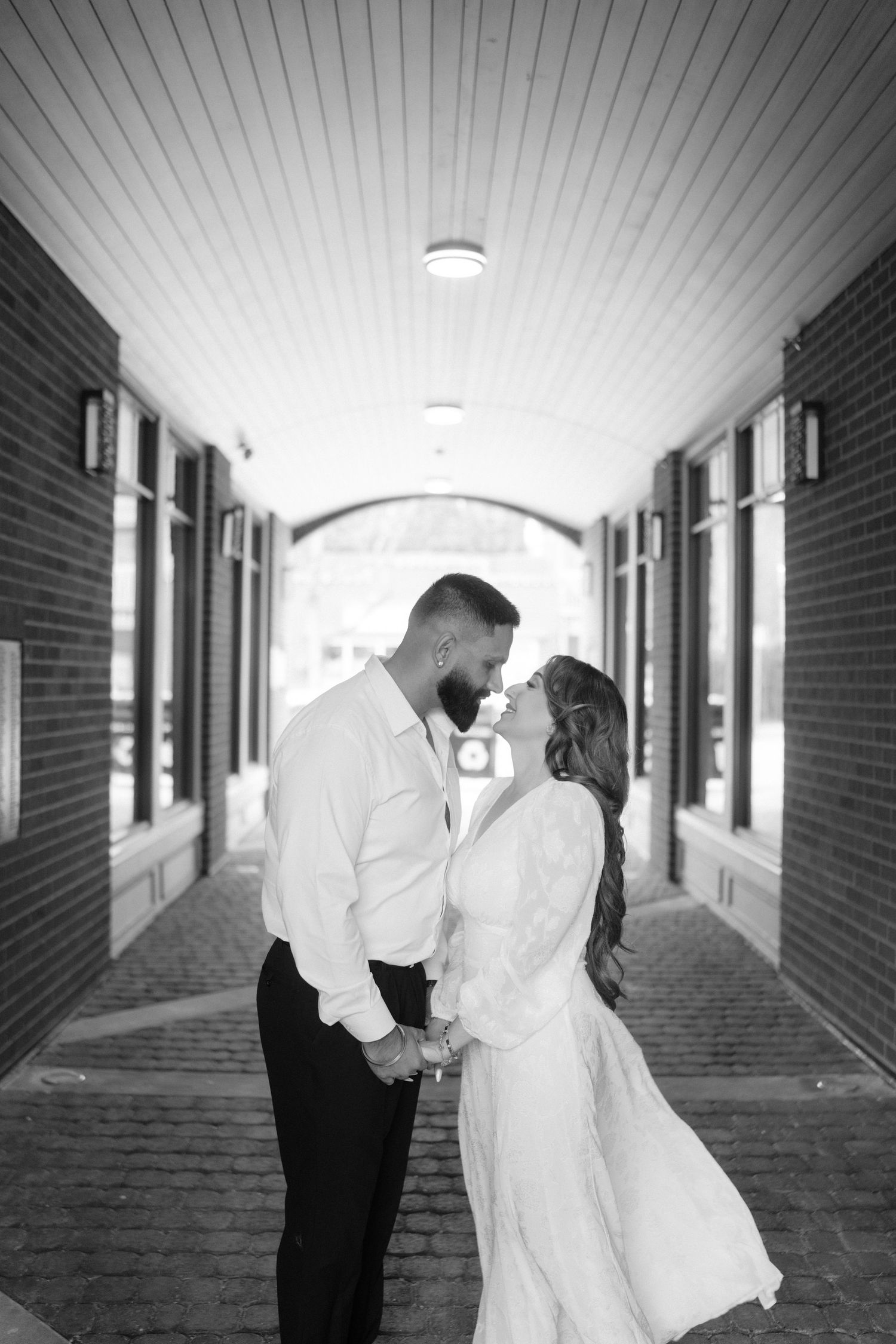 A couple shares intimate moments in a brick-lined hallway with dramatic lighting.