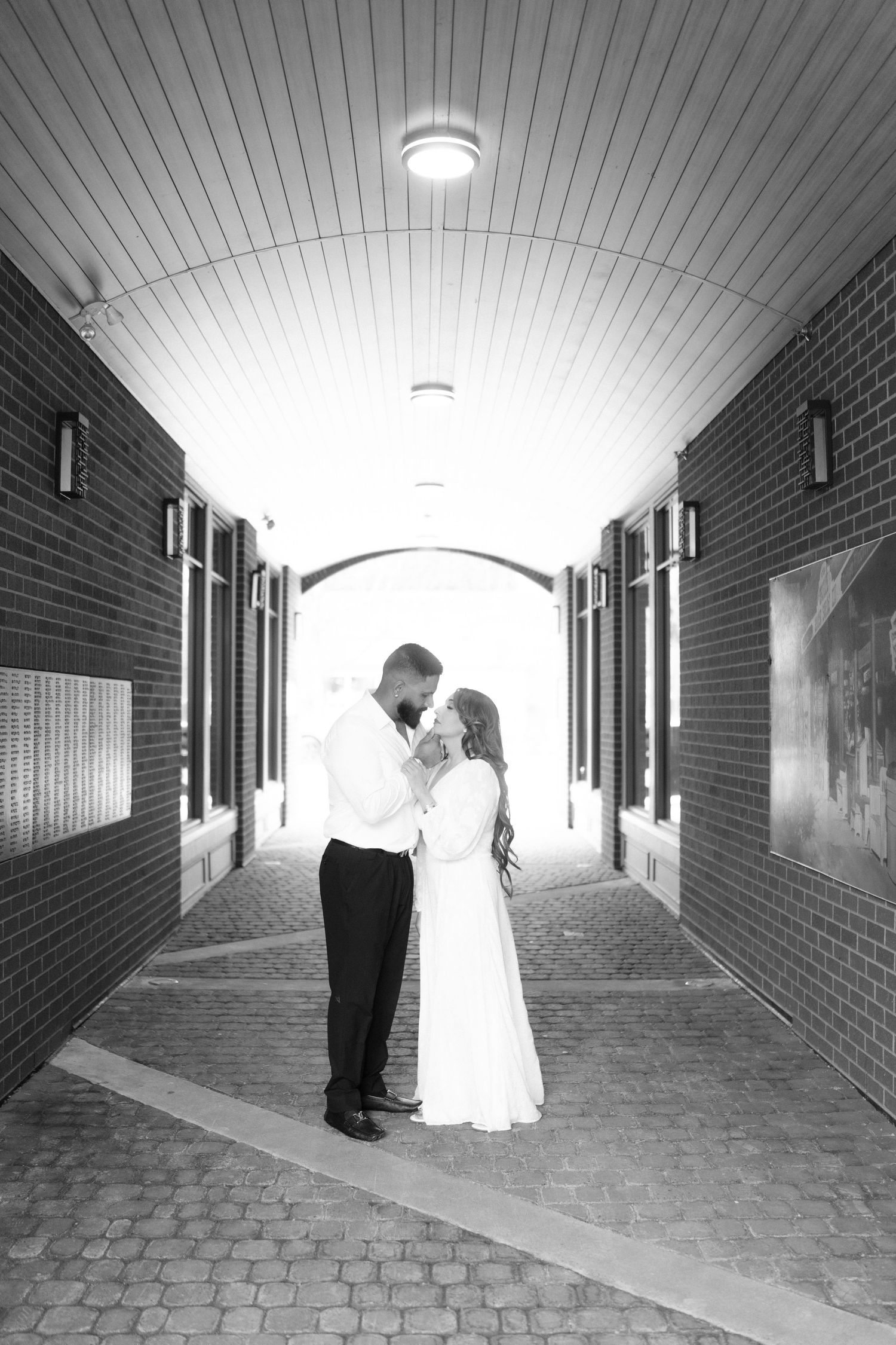 Series of silhouetted figures in a dramatic brick hallway with natural lighting.