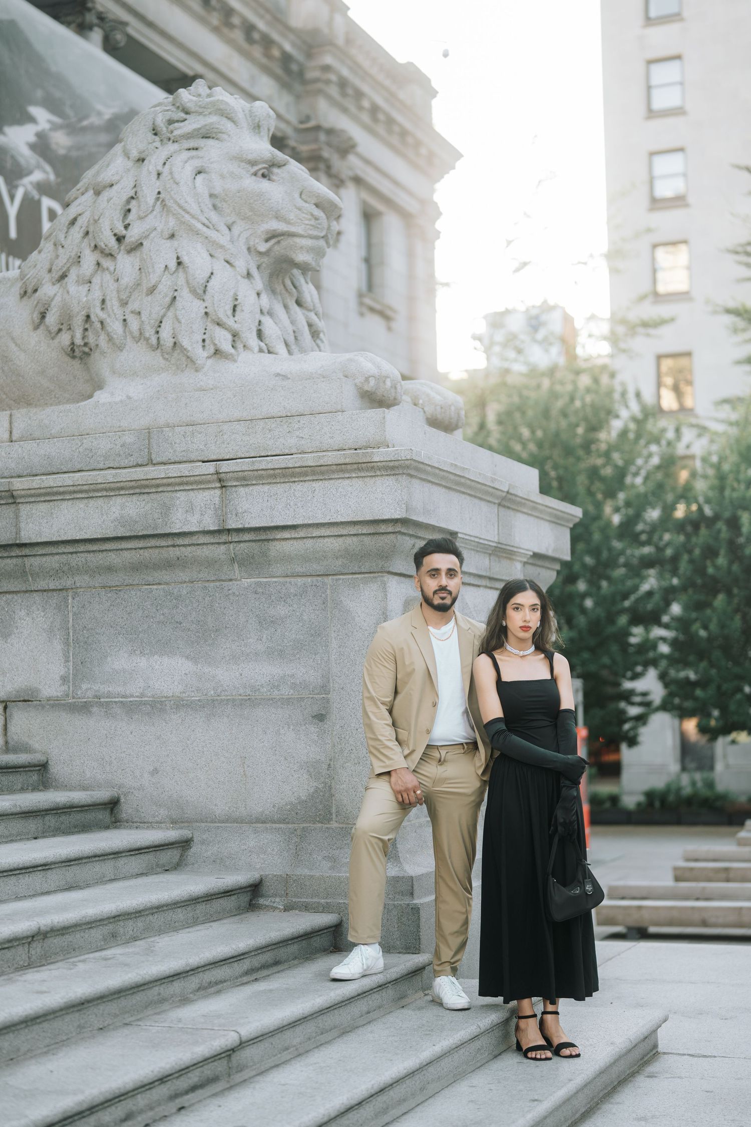 A couple poses together on elegant stone steps outside a grand building in a romantic photoshoot setting.