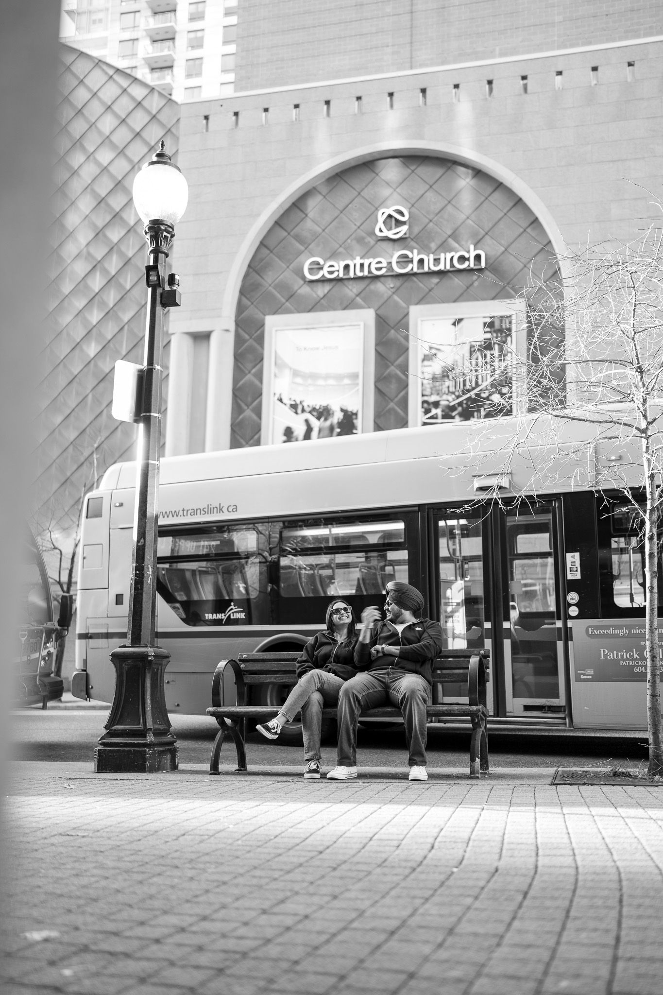A black and white photo series showing a bus stop with passengers waiting under an arched transit station entrance.