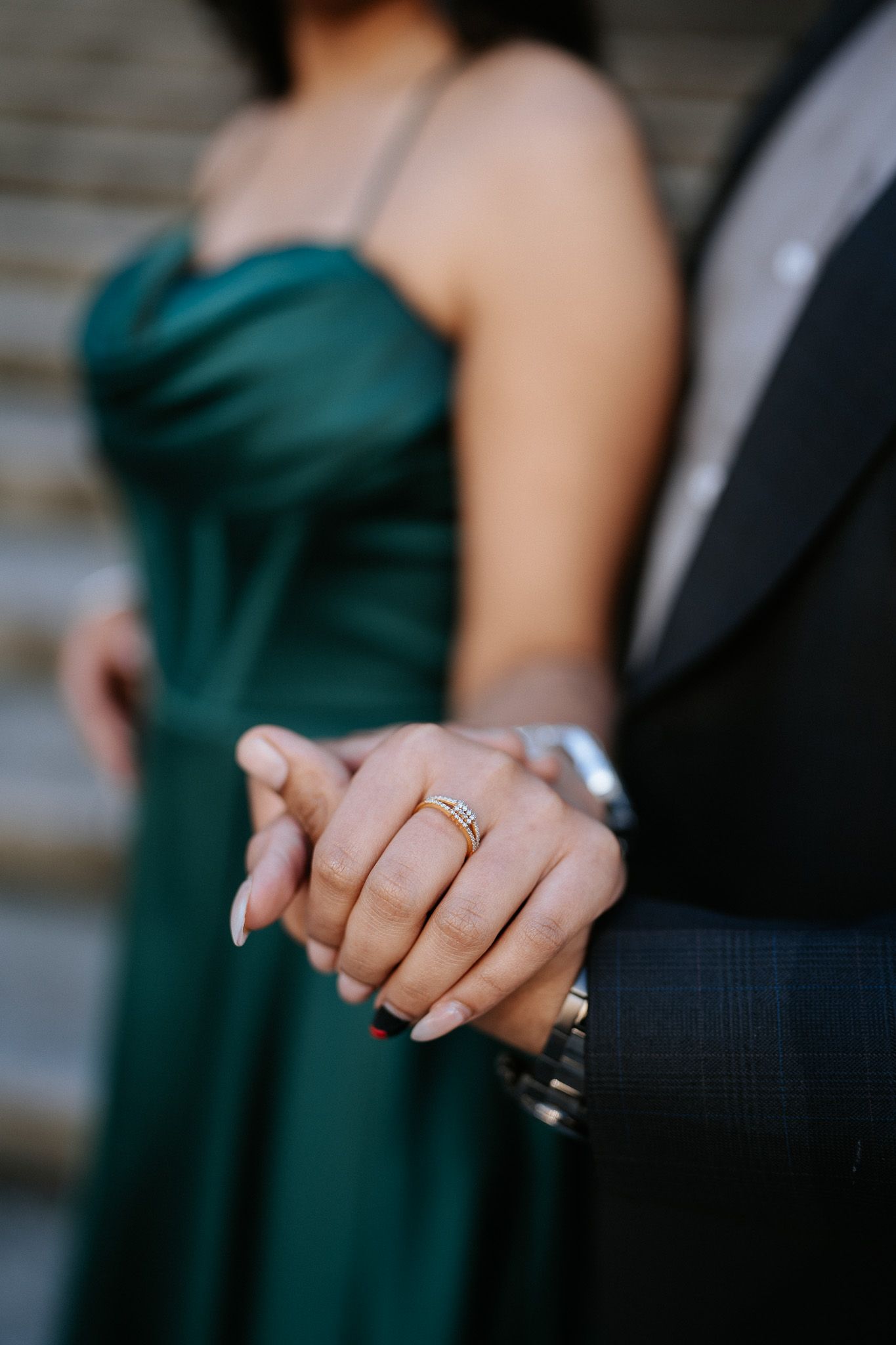 Close-up shots of hands wearing wedding rings against emerald green dress and black suit details.