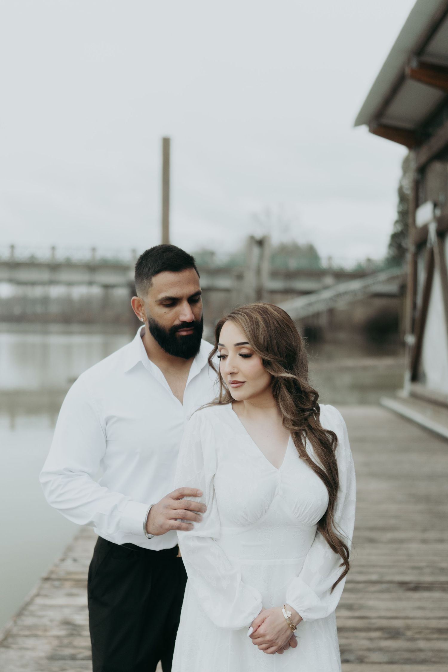 A couple shares tender moments during their photoshoot on a wooden pier.