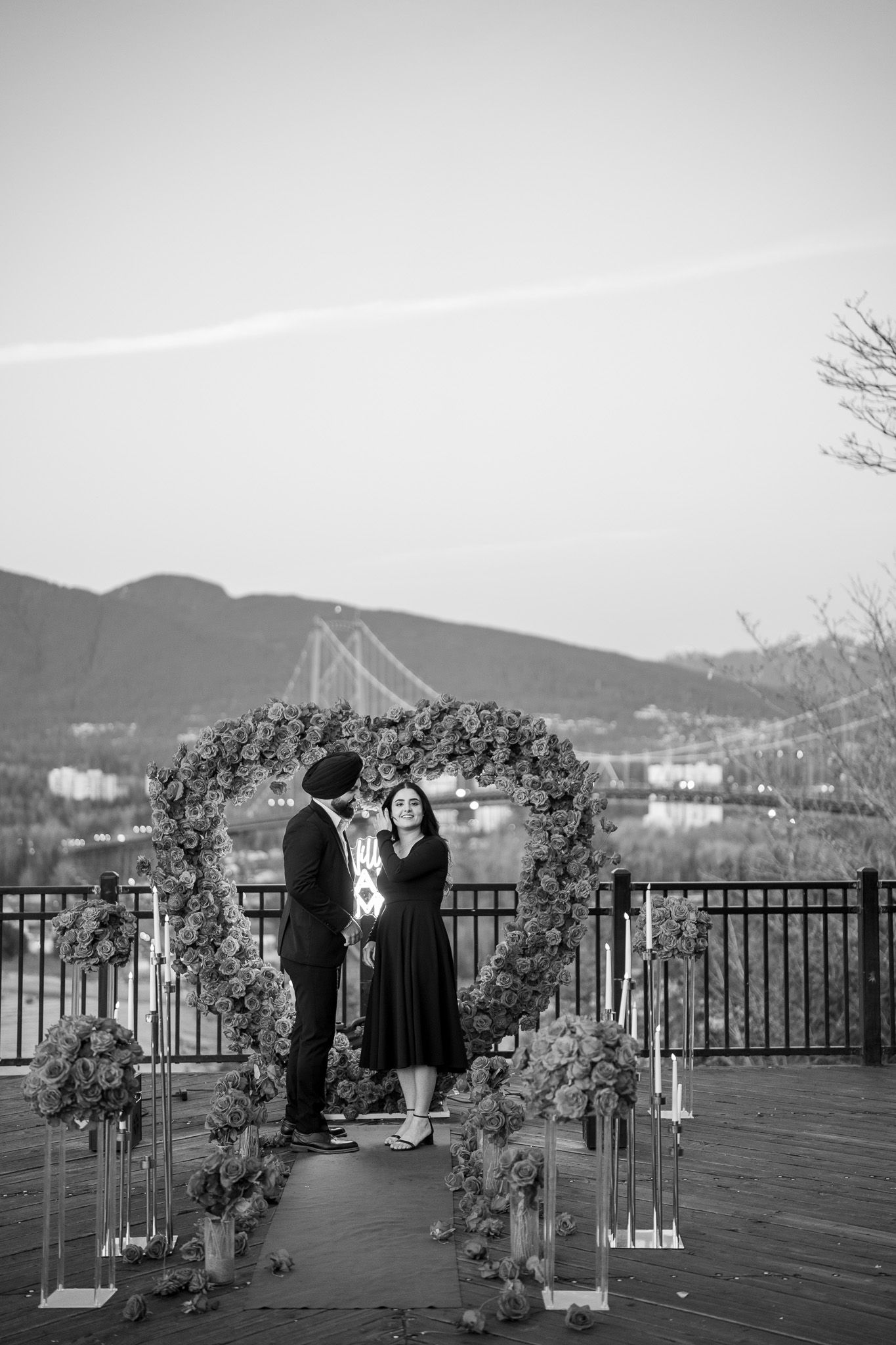 A wedding ceremony setup on an outdoor deck overlooking mountains with a decorated floral arch and chairs.