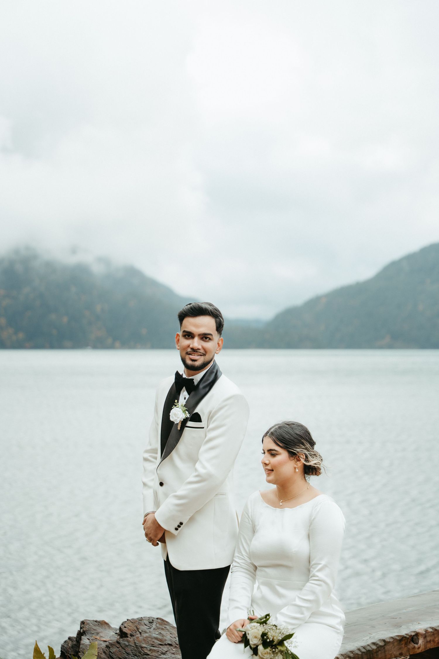 Couple shares a joyful moment together on a misty lakeside with mountains in the background.