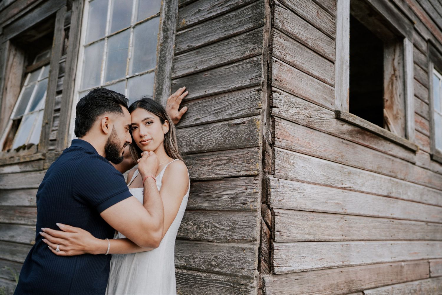 A romantic couple embraces against a rustic wooden wall in a series of intimate wedding photos.